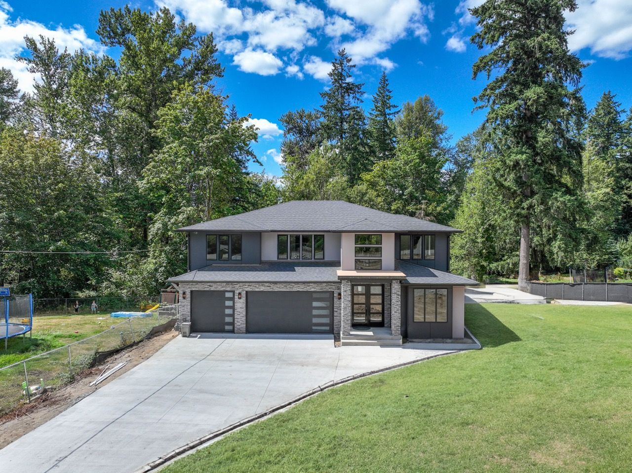 A large house is sitting on top of a lush green hill surrounded by trees.