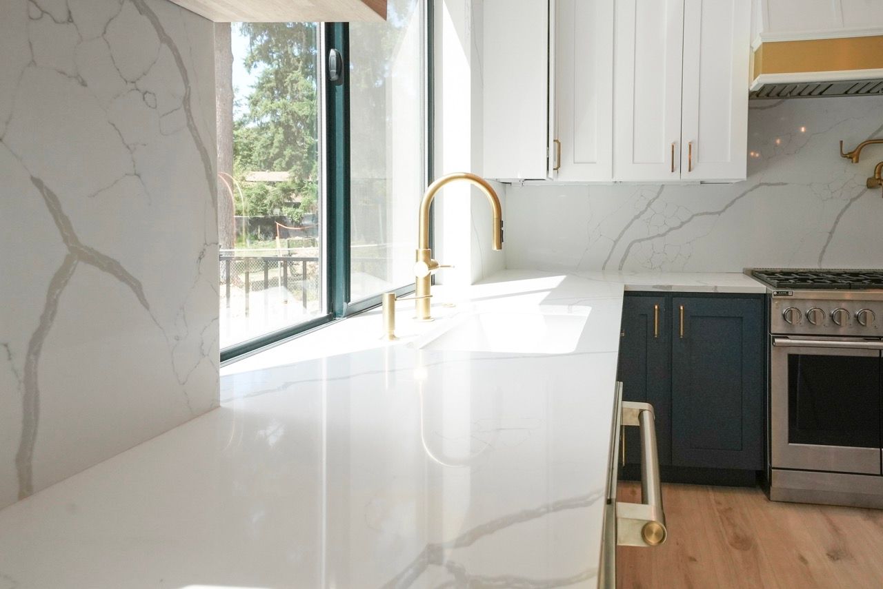 A kitchen with a sink , stove , and window.
