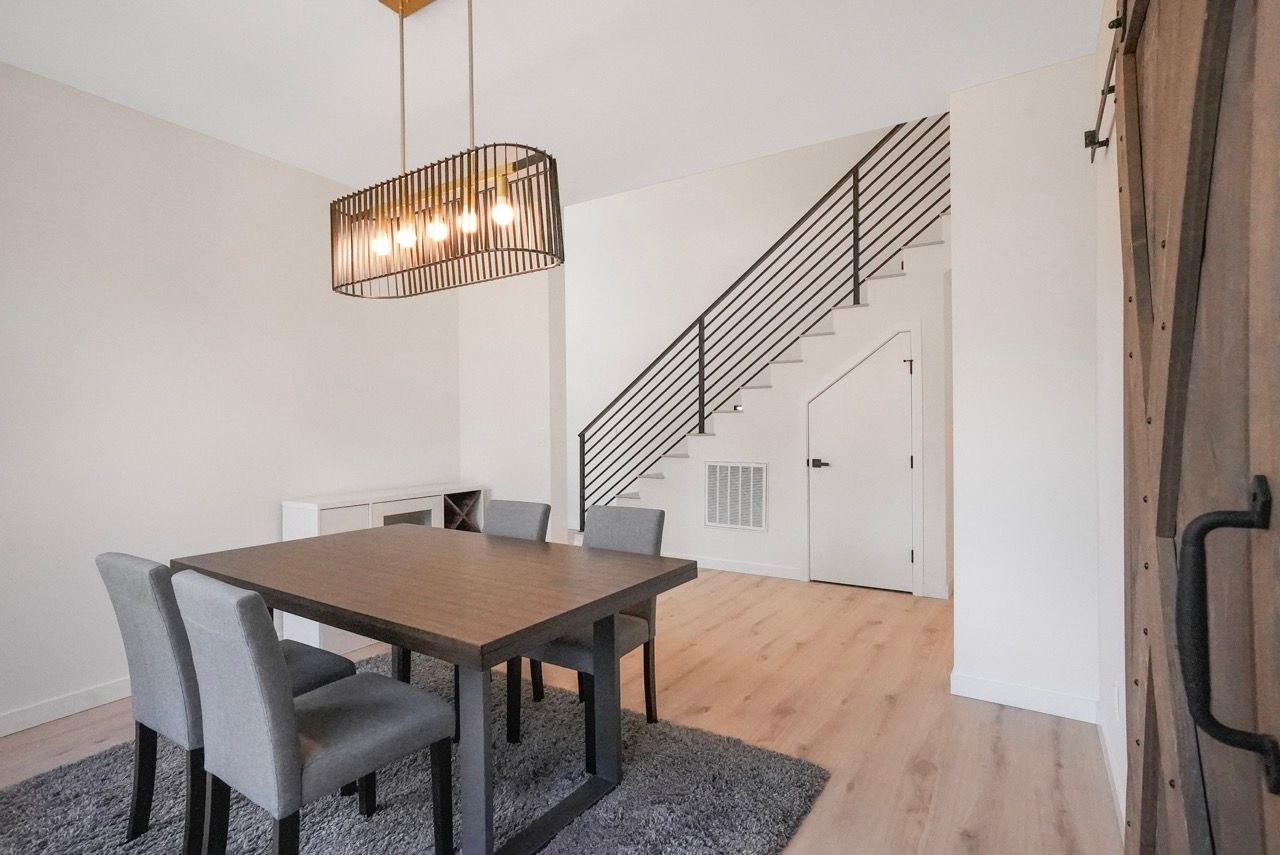 A dining room with a table and chairs and a staircase.
