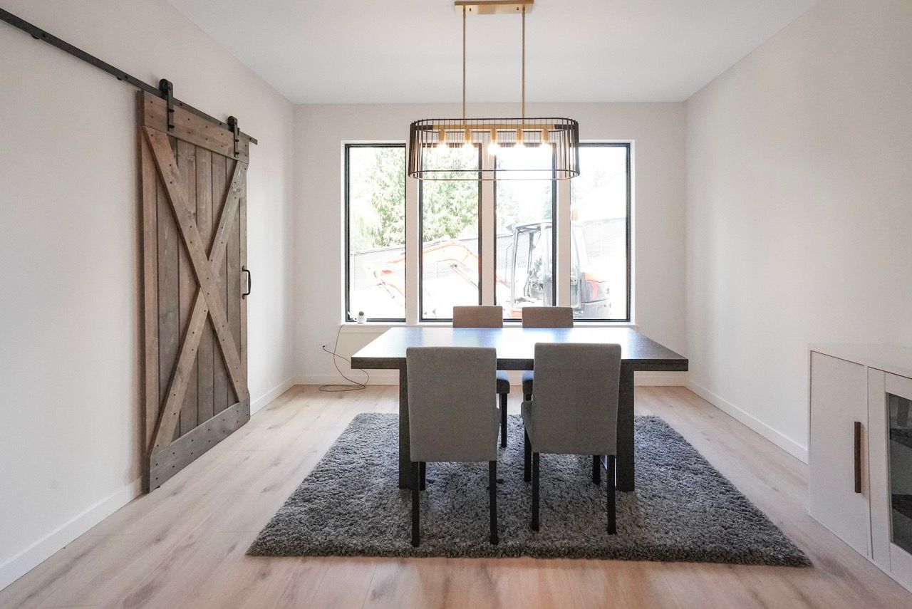 A dining room with a table and chairs and a sliding barn door.