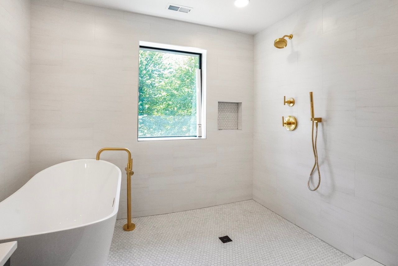 A bathroom with a bathtub , shower , and window.