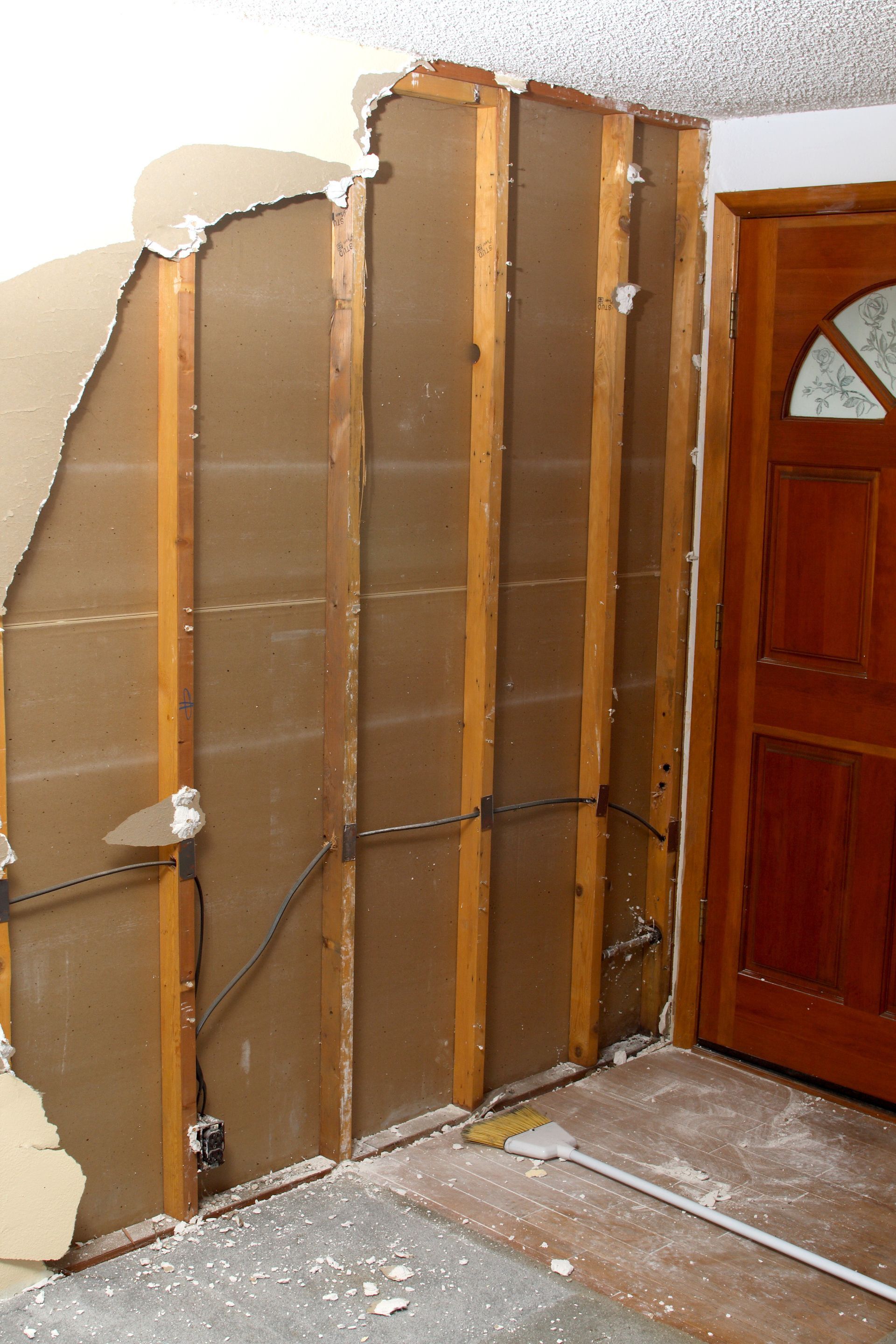 A corner of a room with a wooden floor and a dirty wall.