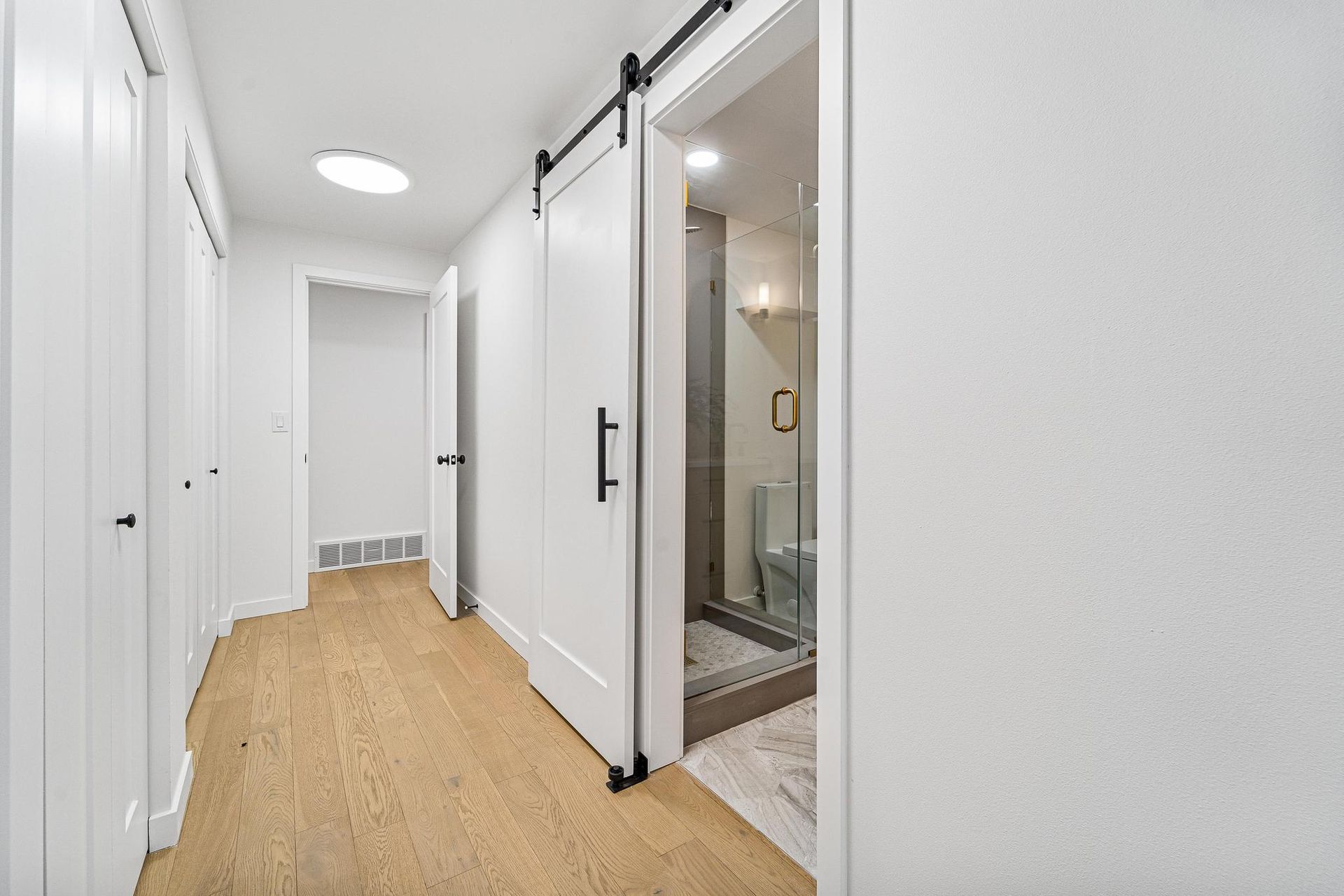 A hallway with sliding barn doors leading to a bathroom.