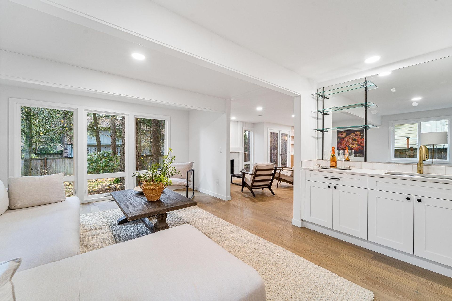 A living room with a couch , coffee table , chairs and a large mirror.