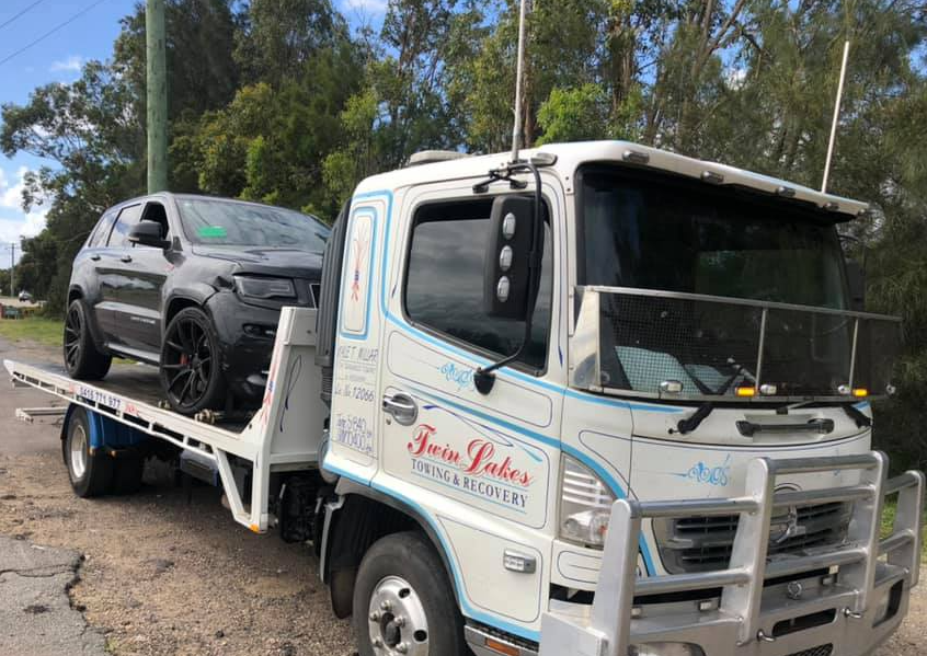 White Truck Towing Black Car — Roadside Assist Central Coast in Hamlyn Terrace, NSW