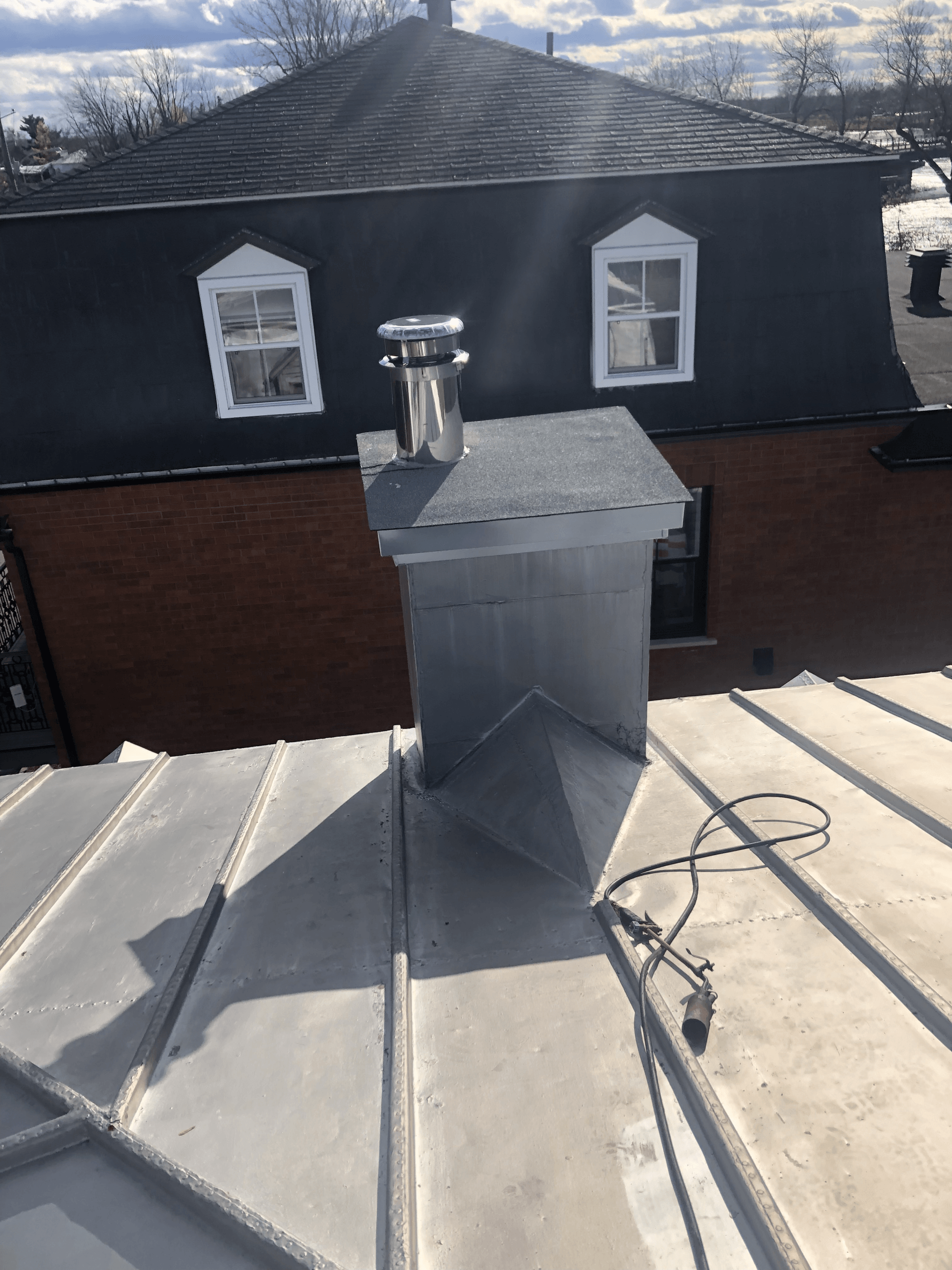 Une cheminée sur le toit d'une maison avec un bâtiment en brique en arrière-plan.