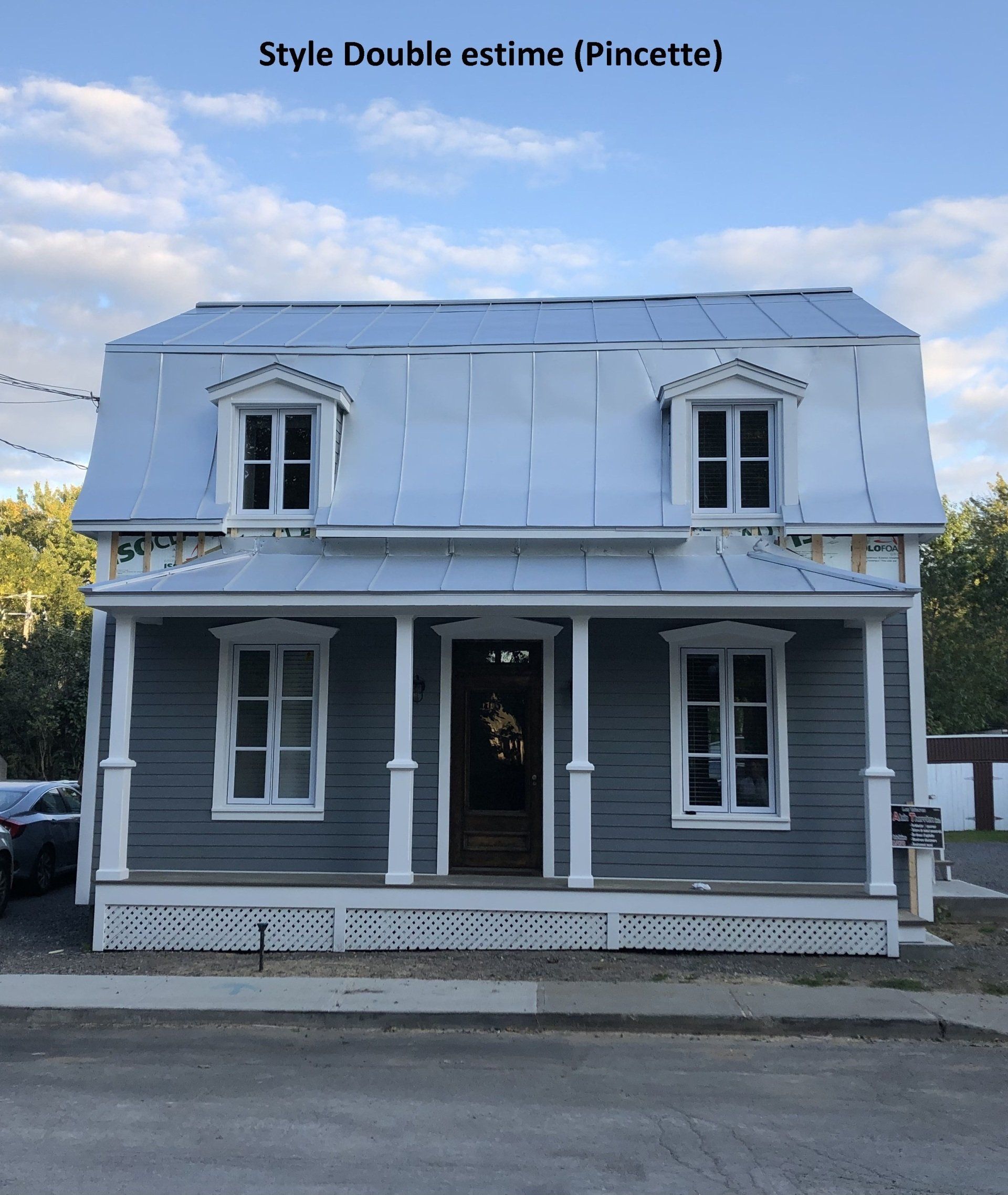 Une maison grise avec un porche blanc et un toit en métal