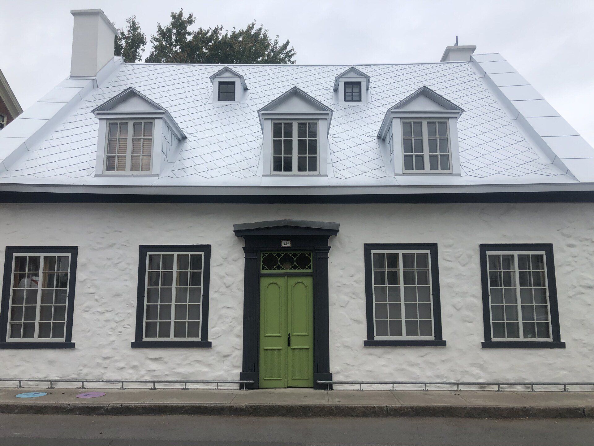 Une maison blanche avec une porte verte et des garnitures noires