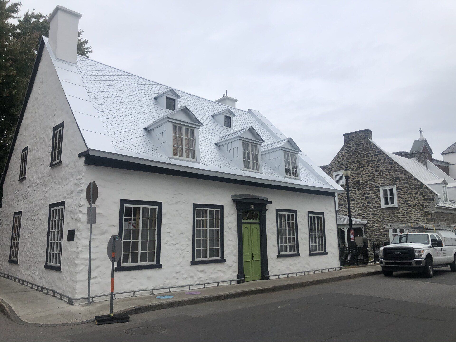 Une maison blanche avec une porte verte se trouve au coin d'une rue.