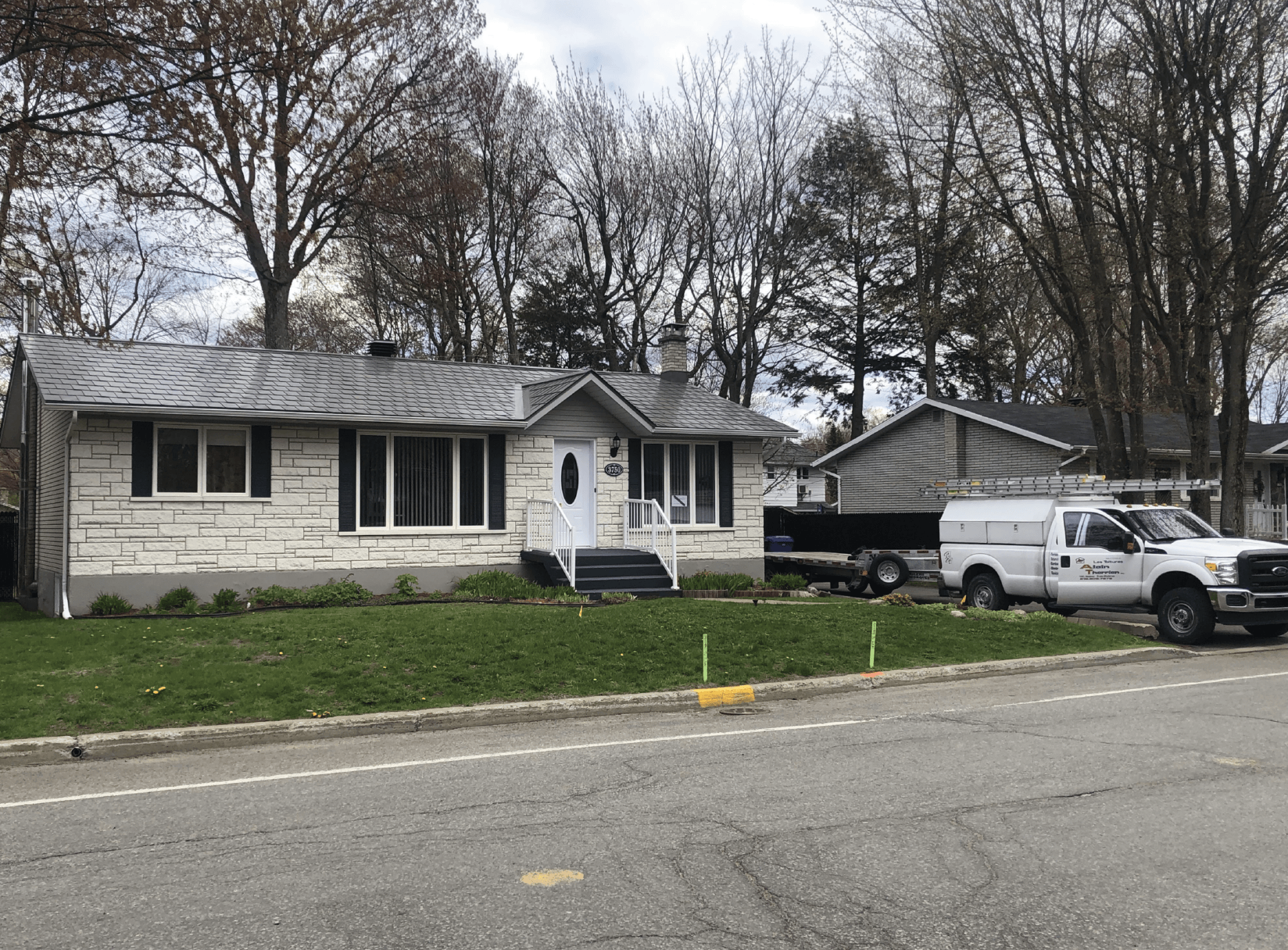 Un camion blanc est garé devant une maison