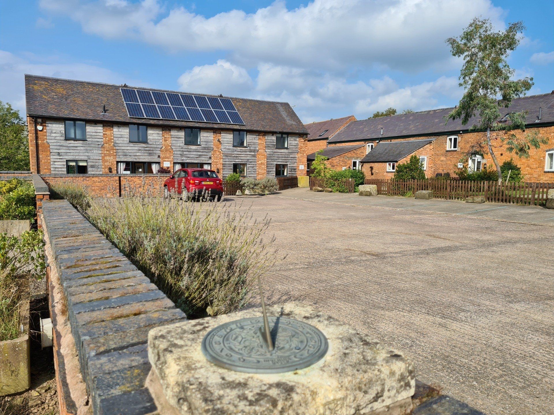 Large empty car park surrounded by holiday cottage at Alkington Grange Barns