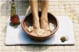 feet in a bowl of water with petals