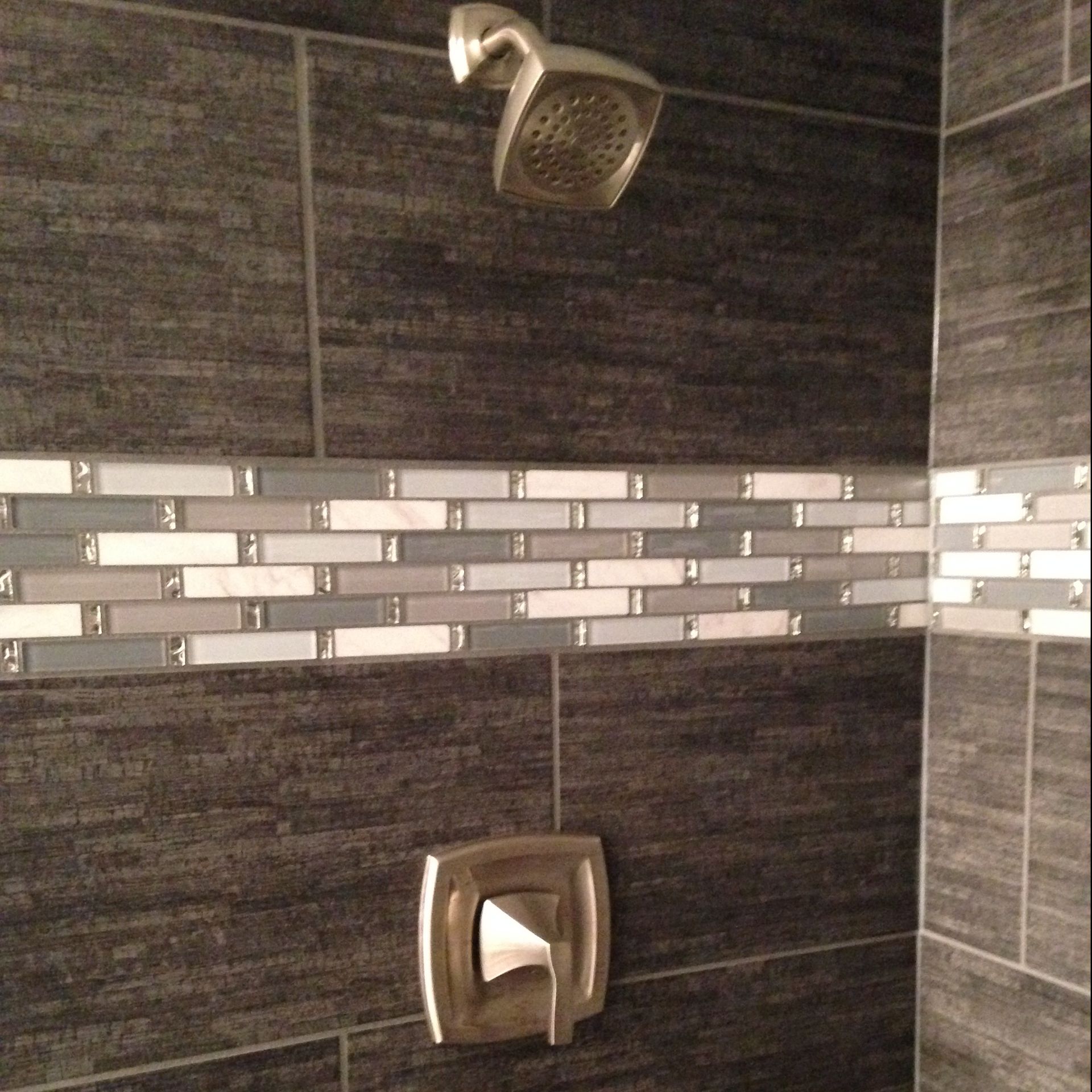 Shower with dark gray tile, mosaic accent, and chrome fixtures.