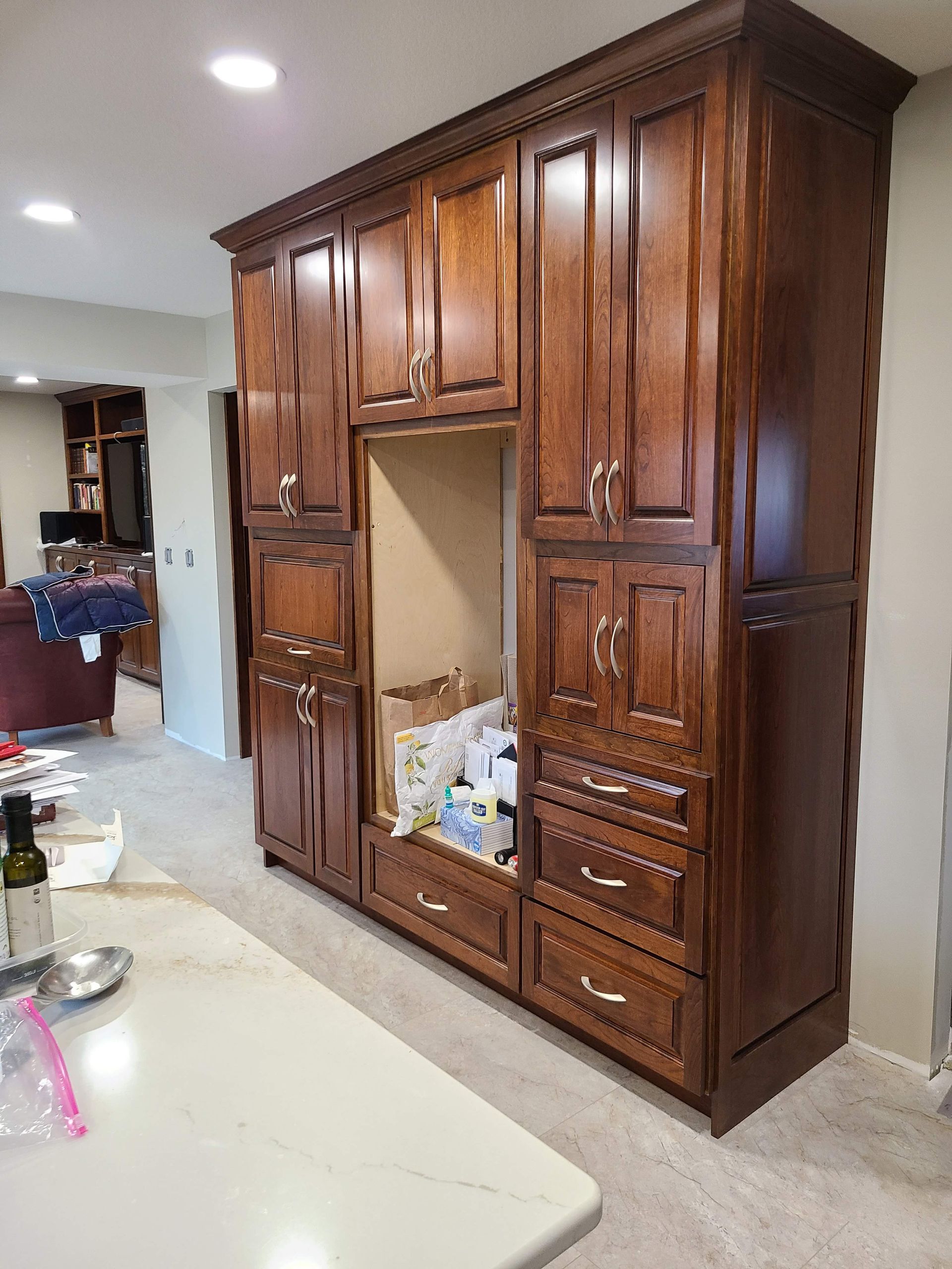 Dark wood kitchen cabinetry with a central appliance niche, drawers, and doors.