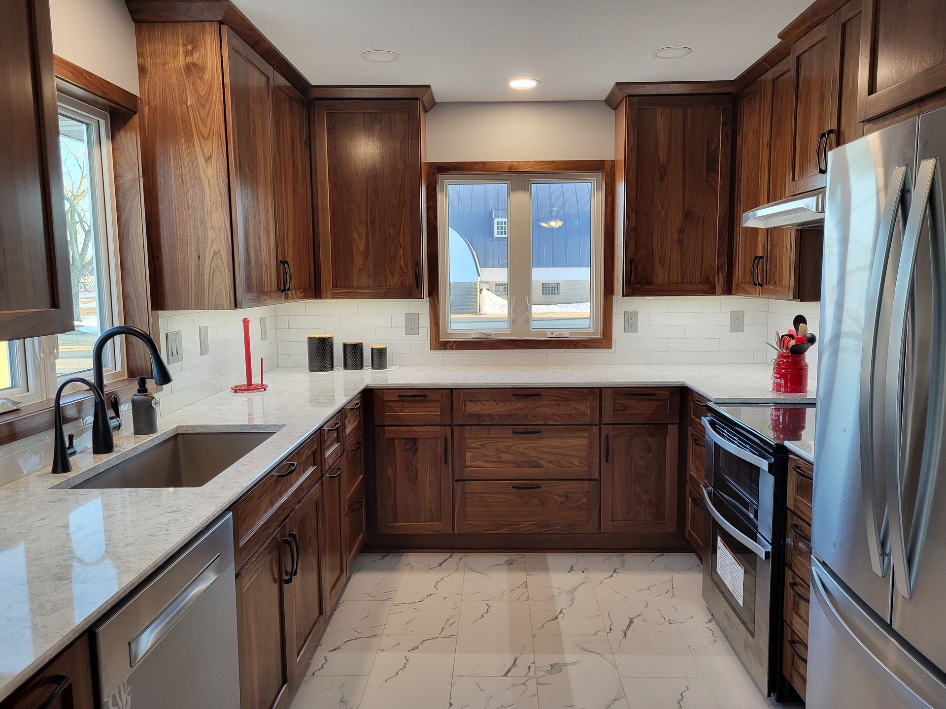 U-shaped kitchen with wood cabinets, white countertops, stainless steel appliances, and a window above the sink.