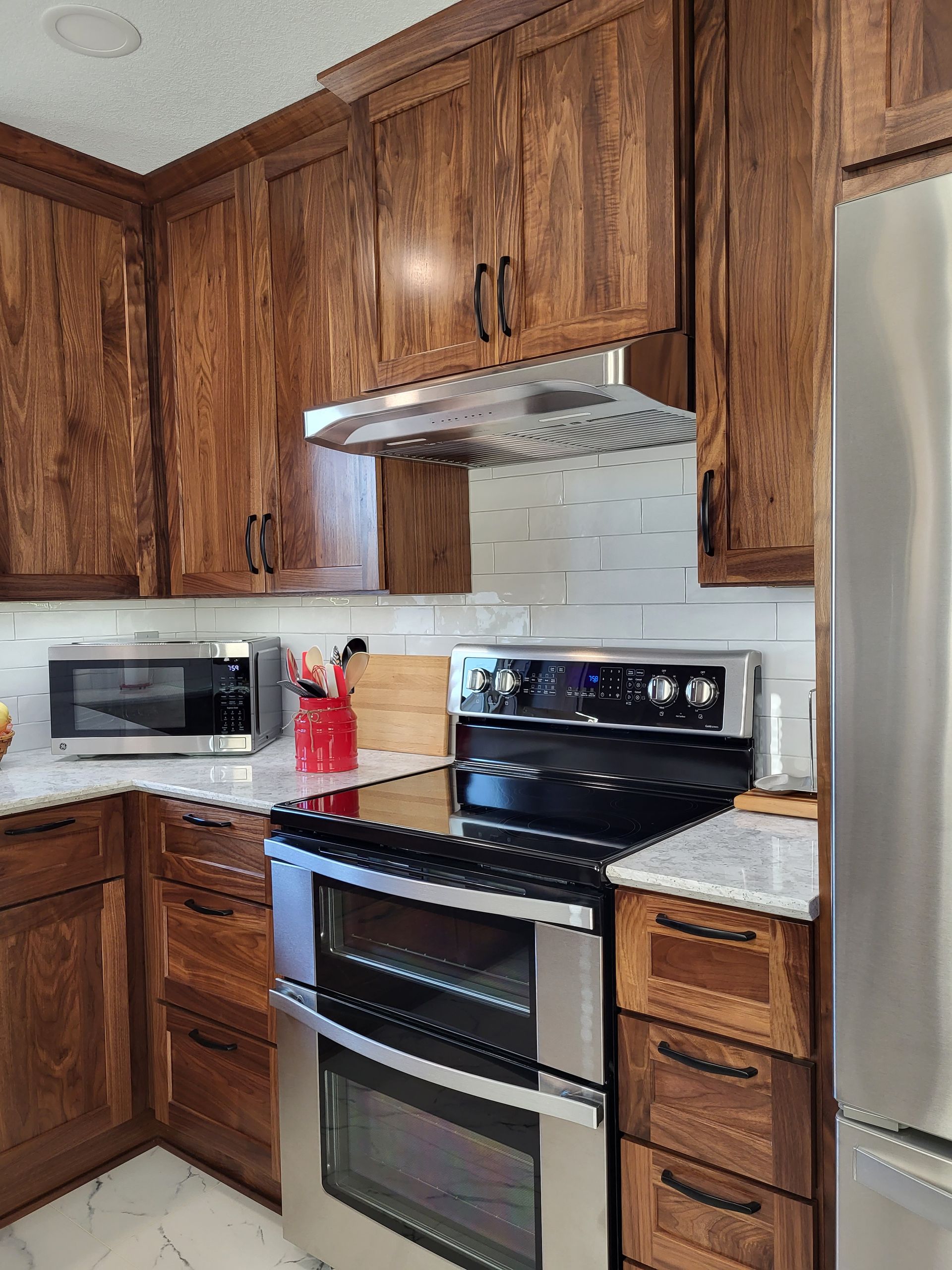 Kitchen with dark wood cabinets, stainless steel appliances, and white backsplash.