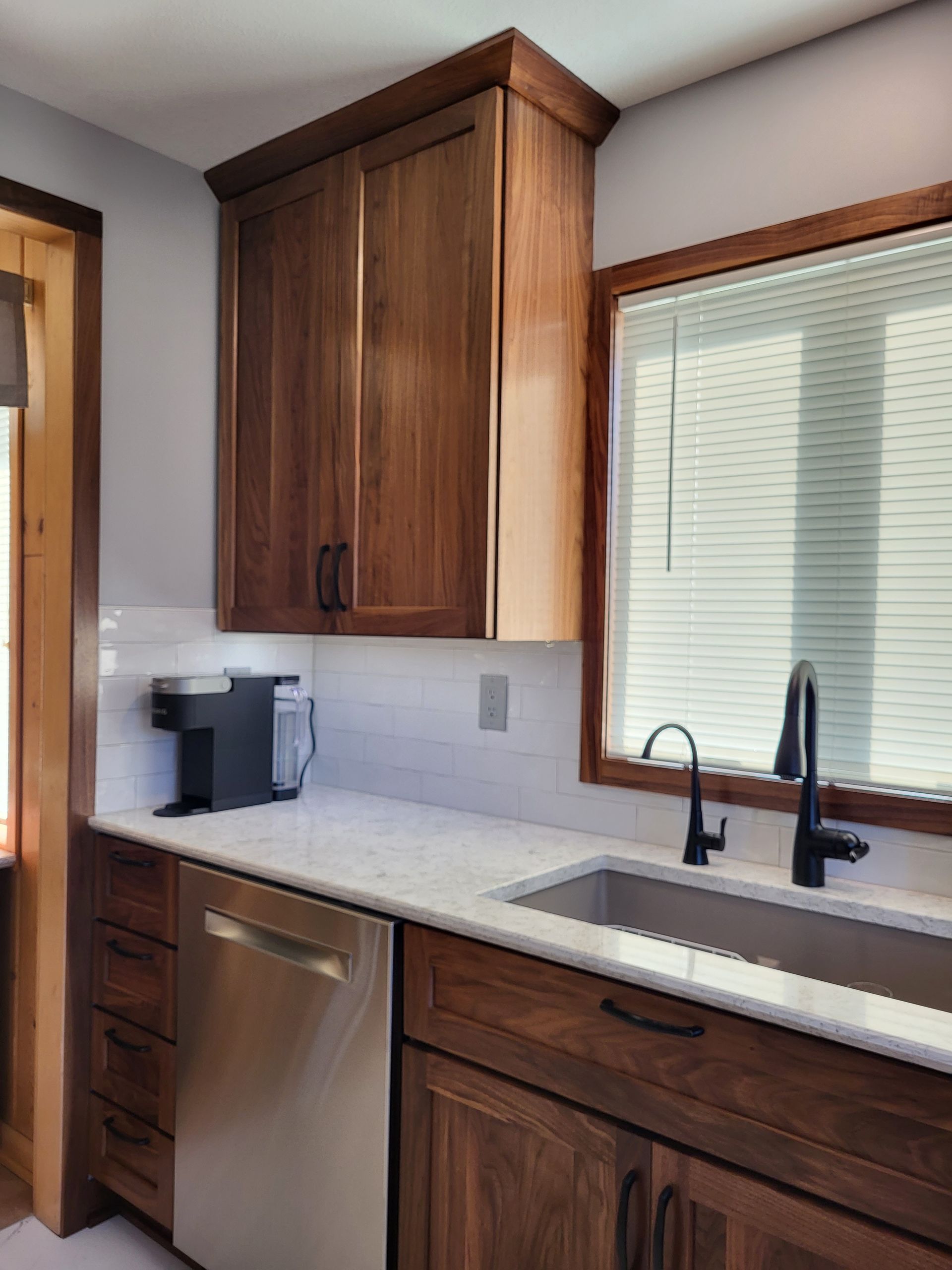 Kitchen with dark wood cabinets, stainless steel appliances, and white countertops.