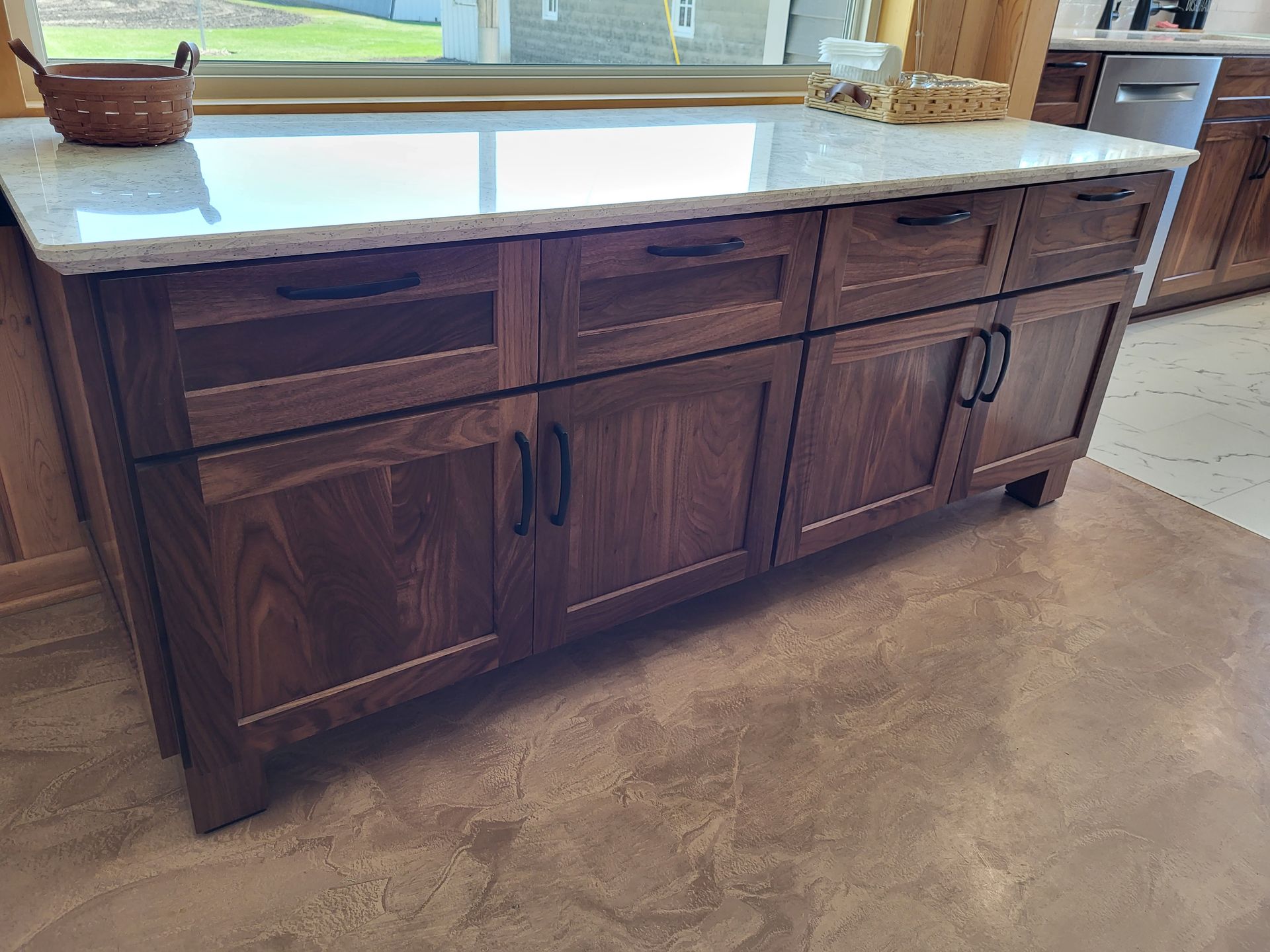 Dark wood kitchen island with white countertop, dark hardware, on a brown floor.