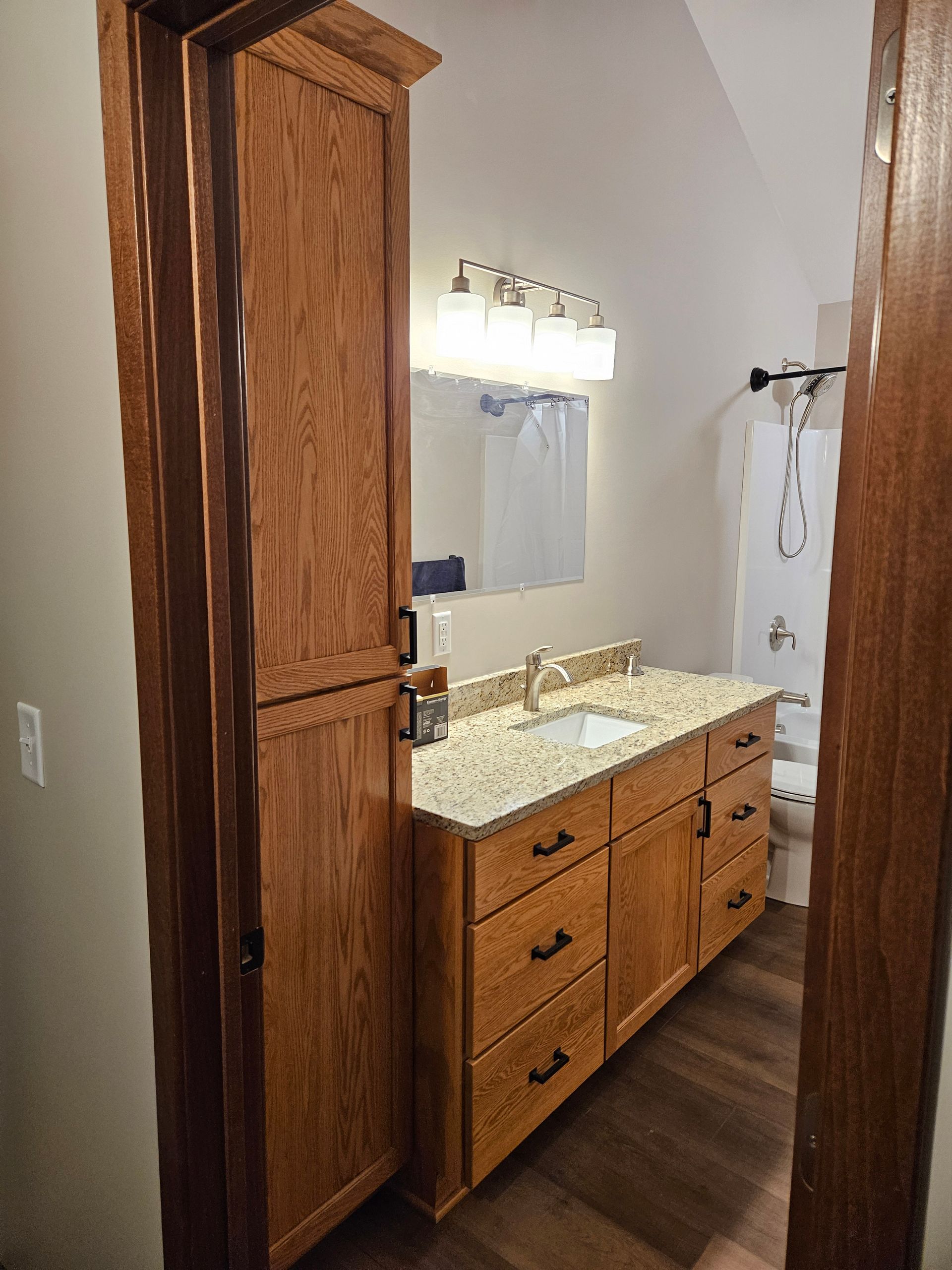 Bathroom with wood cabinets, granite countertop, and vanity mirror.