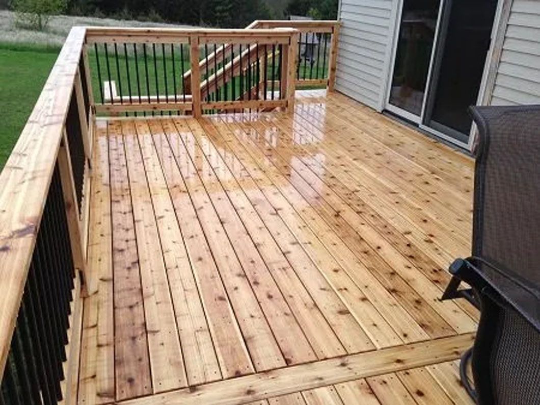 Wooden deck with black railings, a sliding glass door, and a chair.