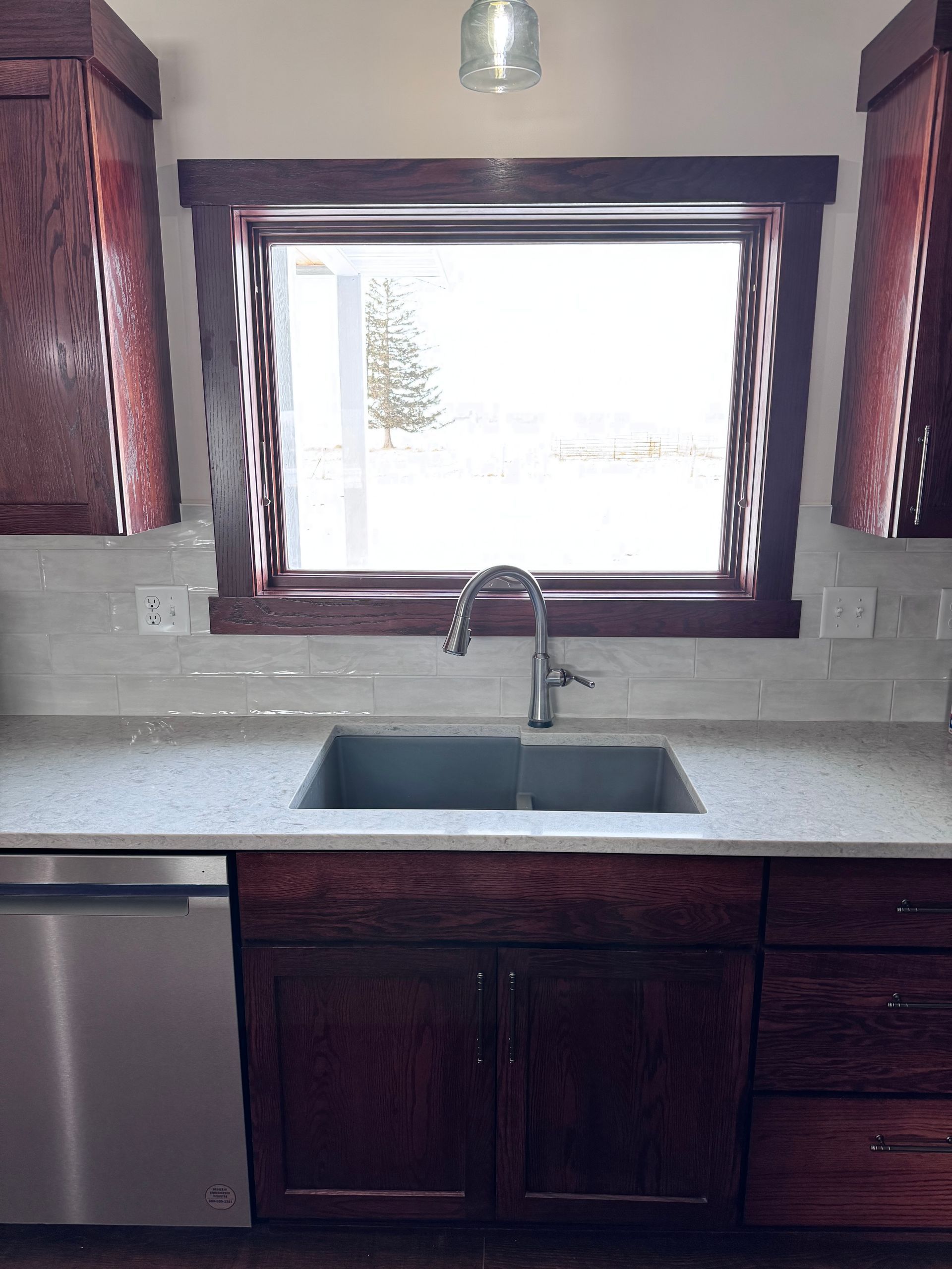 Kitchen with dark wood cabinets, stainless steel sink, and window with a view.