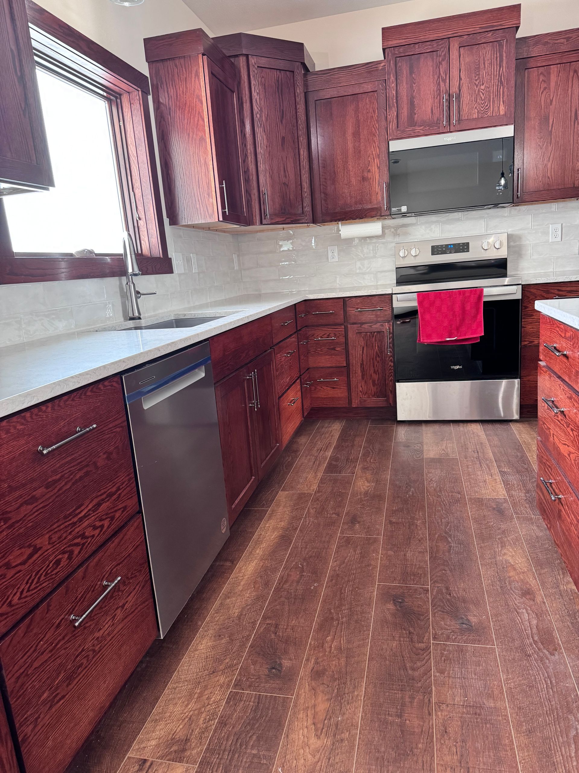 Kitchen with dark wood cabinets, stainless steel appliances, and light countertops.