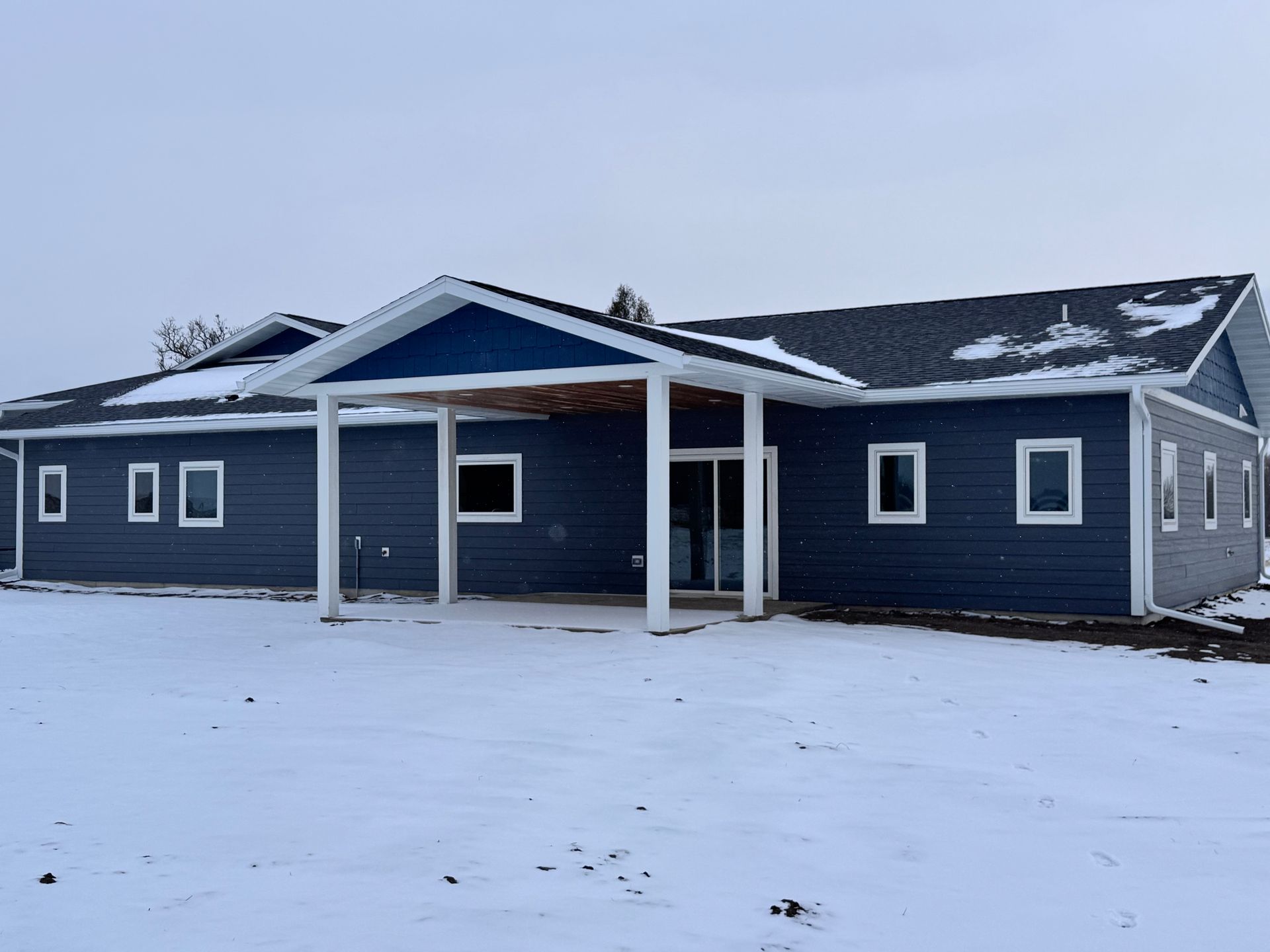 Blue building with white trim, snow-covered ground. Covered entrance.