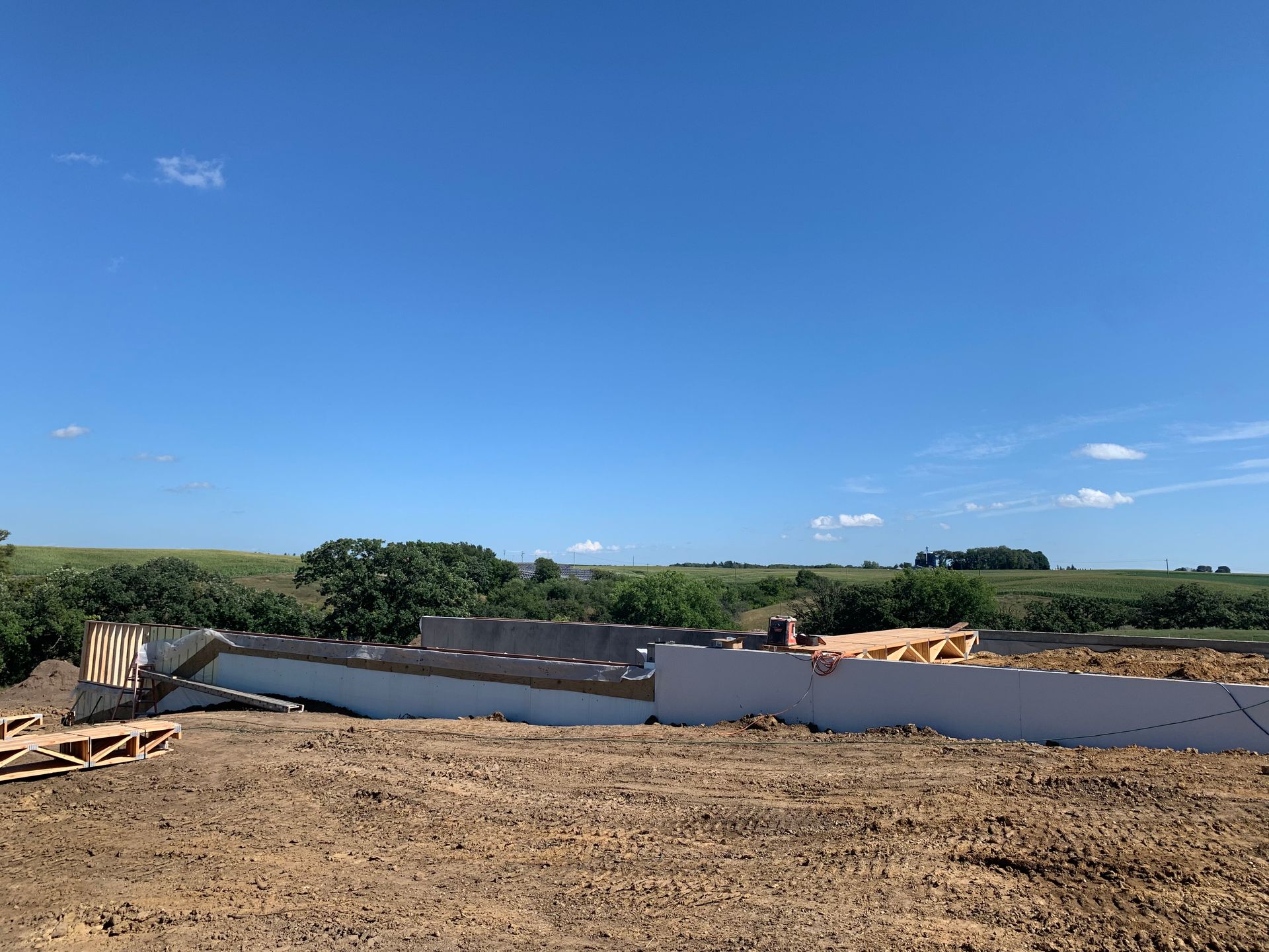 Construction site: foundation walls on dirt under a clear blue sky.