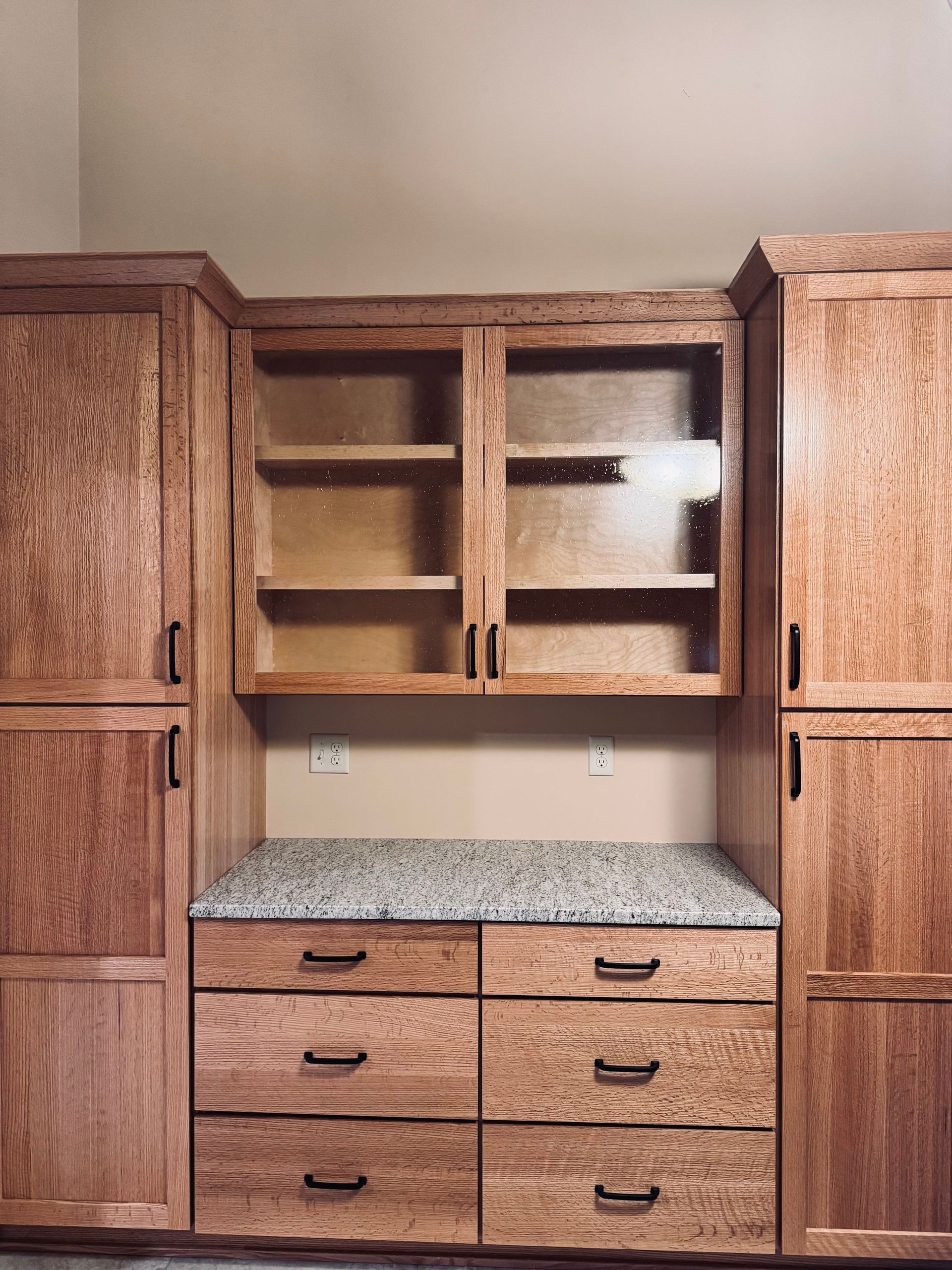 Wooden cabinets with granite countertop and drawers. Two glass-door cabinets above.