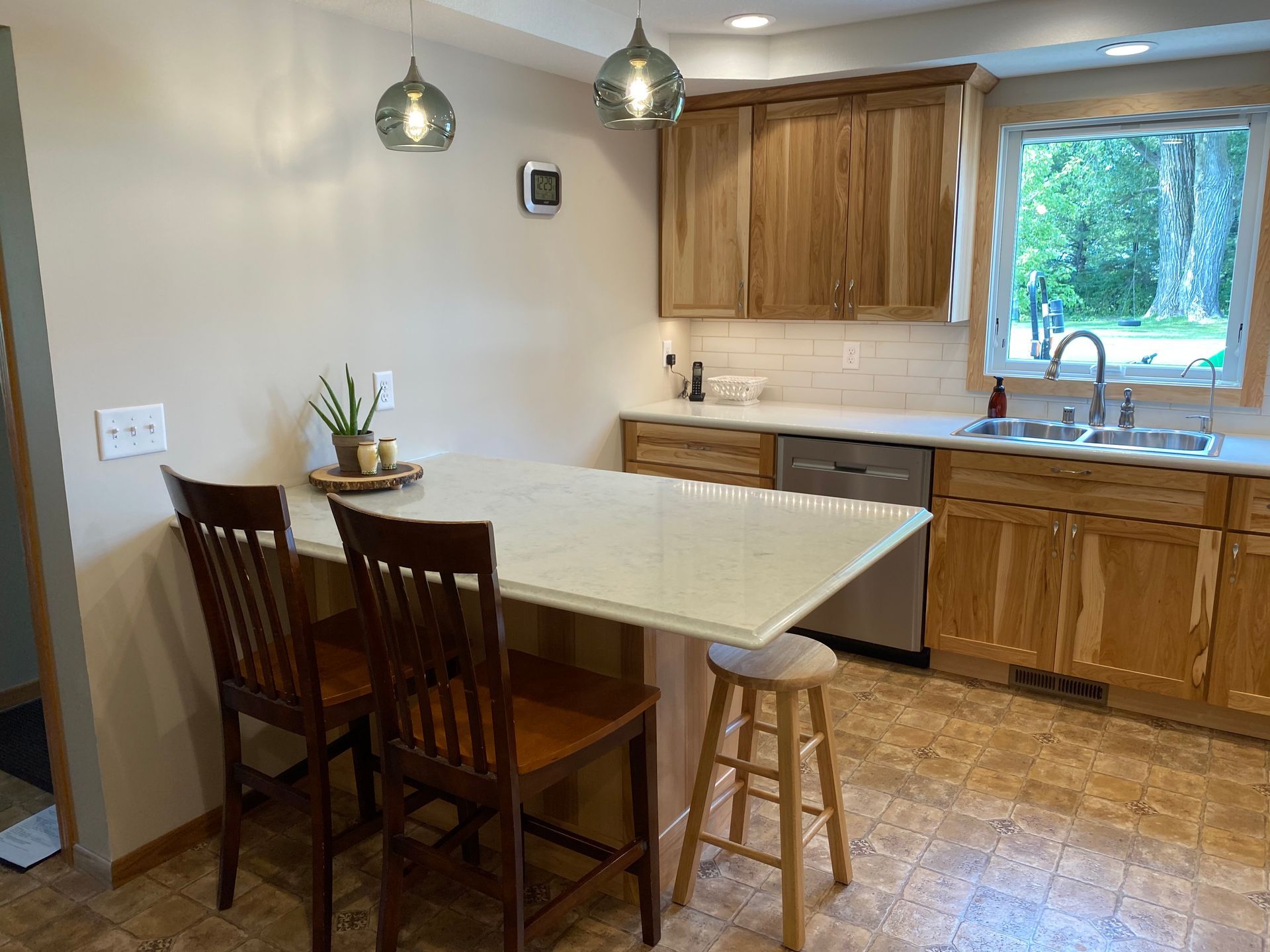 Kitchen with light wood cabinets, a breakfast bar, and a window with outdoor view.