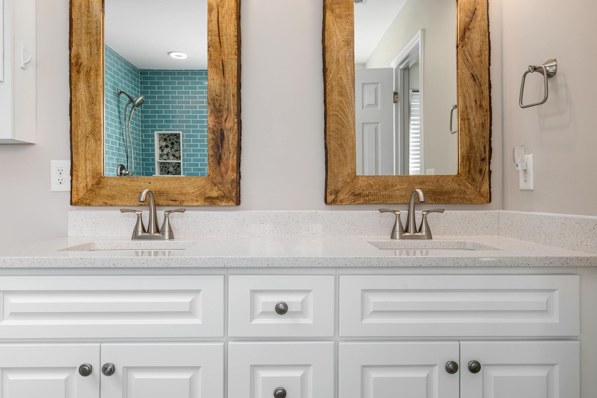 Bathroom with two sinks, white cabinets, speckled countertop, and mirrors with rustic gold frames.