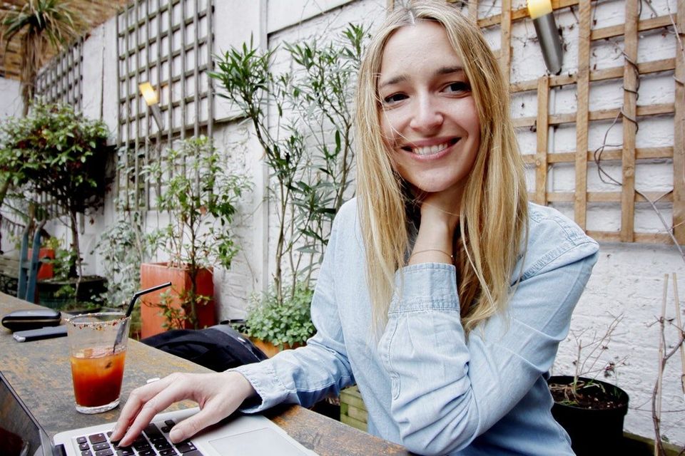 Woman smiling working in a shared space with lots of plants