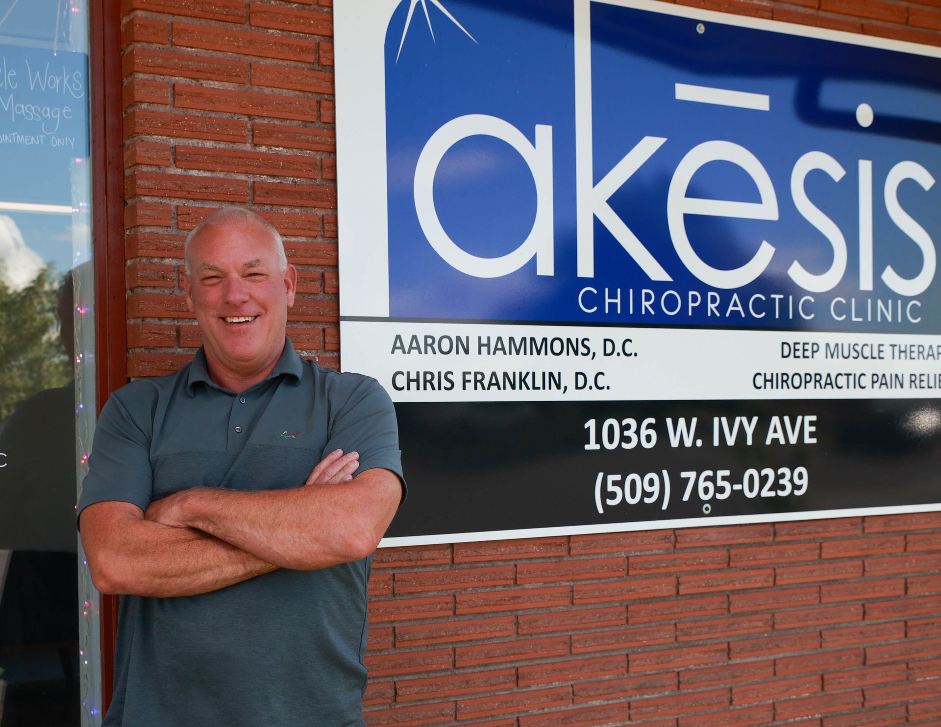 A man is standing in front of a sign for akesis chiropractic clinic