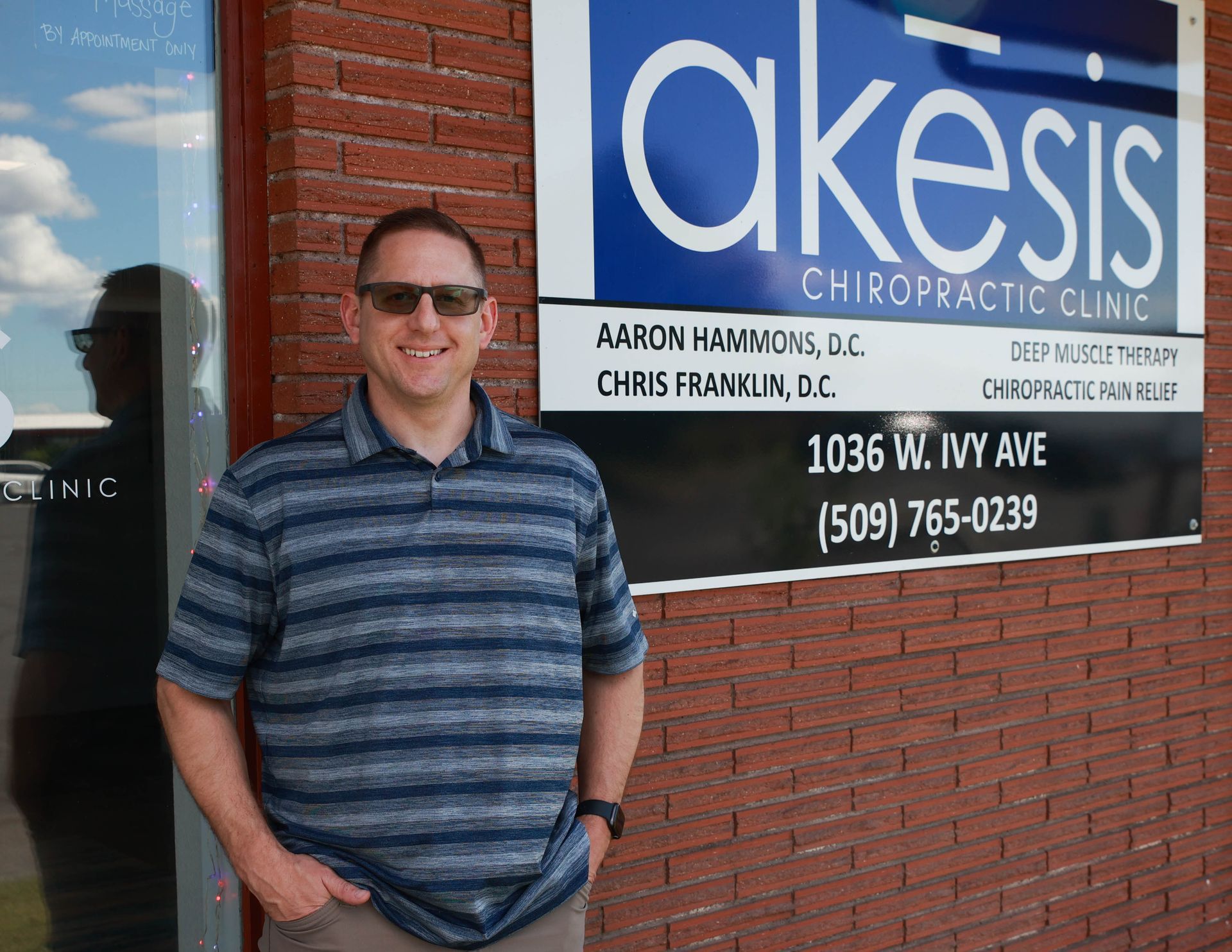A man stands in front of a sign for akesis chiropractic clinic