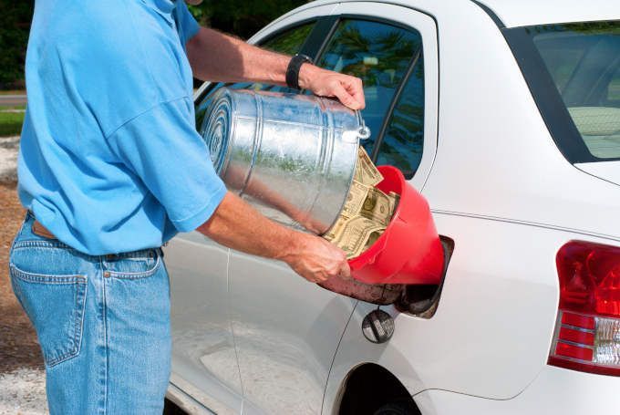 Image of a man literally funneling cash into his gas tank