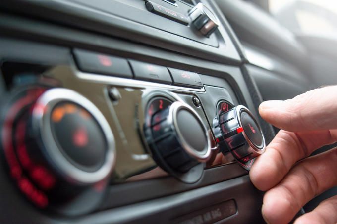 Image of hands operating the heating controls inside a vehicle