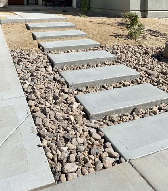 A gravel path with evenly spaced rectangular concrete pavers leading toward a building entrance.