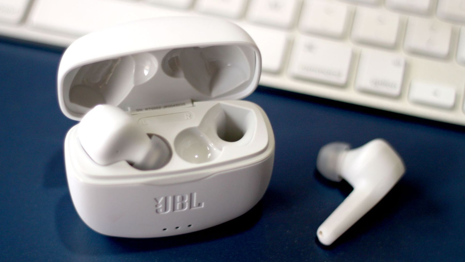 Um par de fones de ouvido jbl brancos ao lado de um teclado