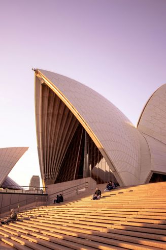 Um grupo de pessoas está sentado nos degraus da Ópera de Sydney.