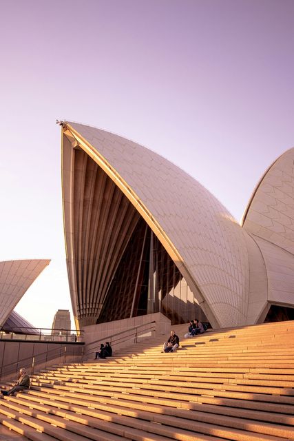 Um grupo de pessoas está sentado nos degraus da Ópera de Sydney.