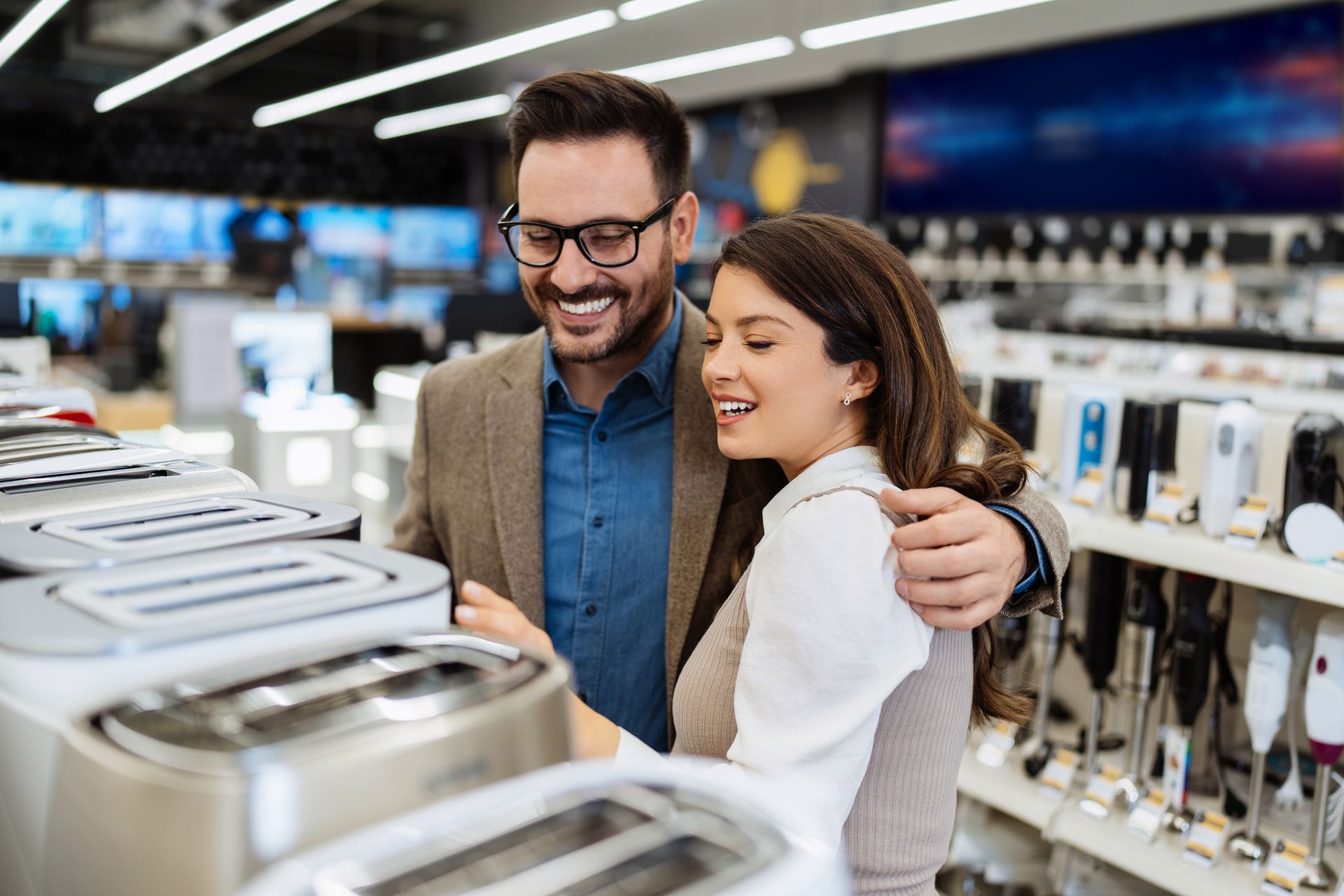 un hombre y una mujer están mirando una tostadora en una tienda .