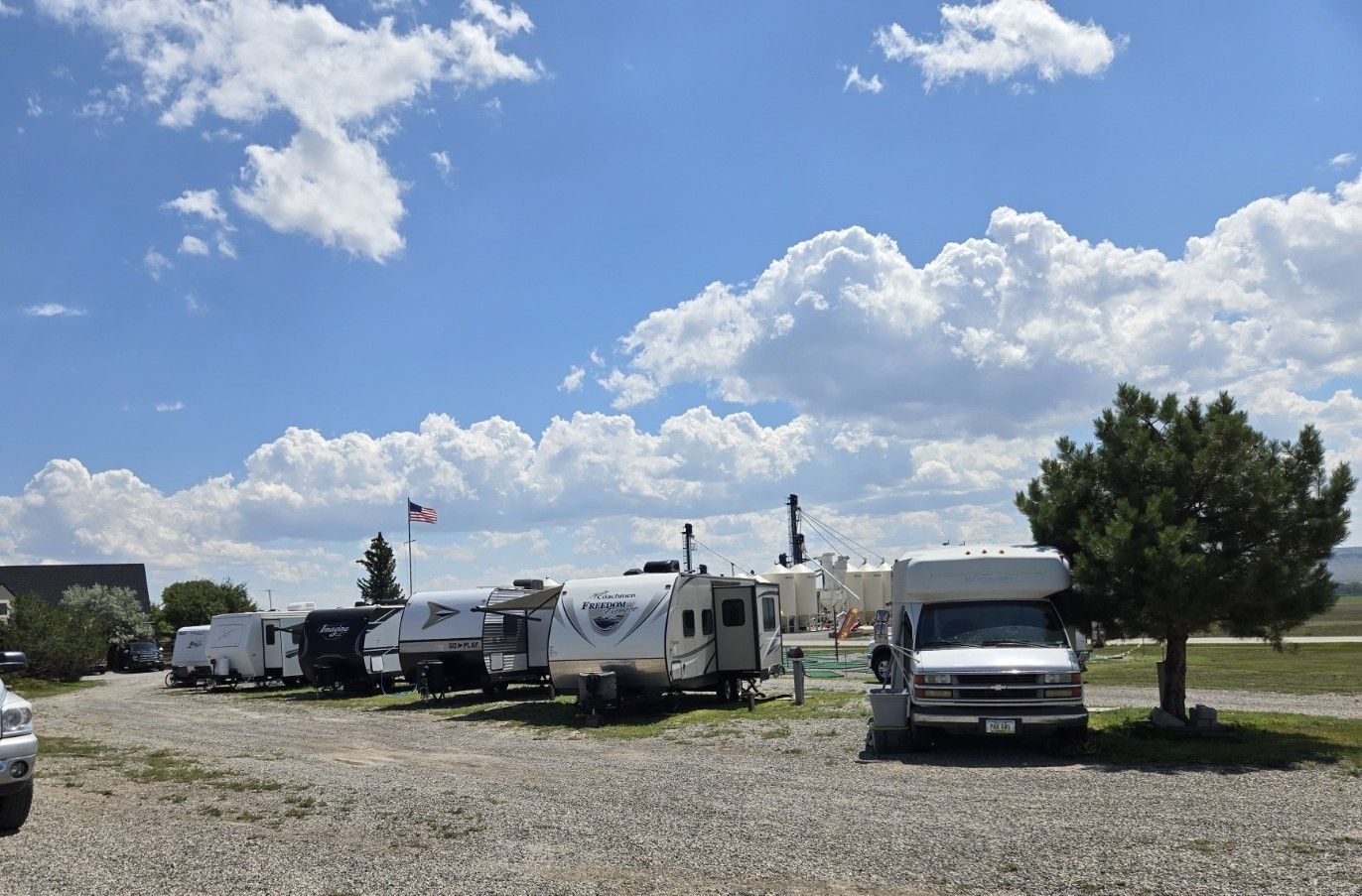 Campground with RVs parked on gravel under a cloudy sky.