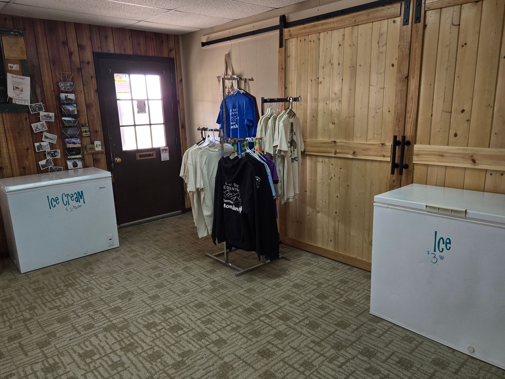 Clothing display in store with wooden walls, freezer on each side, door.