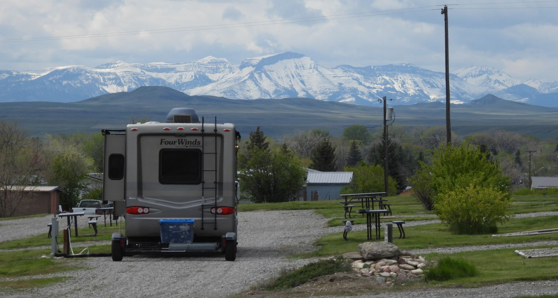 RV parked at campsite with snowy mountains in the background.