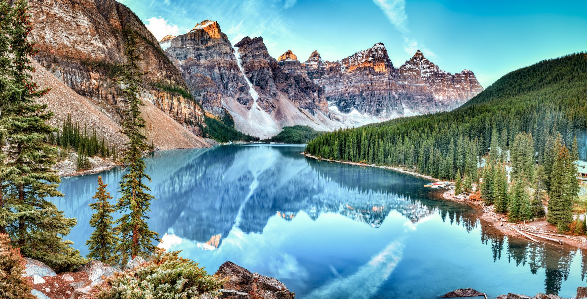 Blue lake with mountain backdrop and evergreen forest.