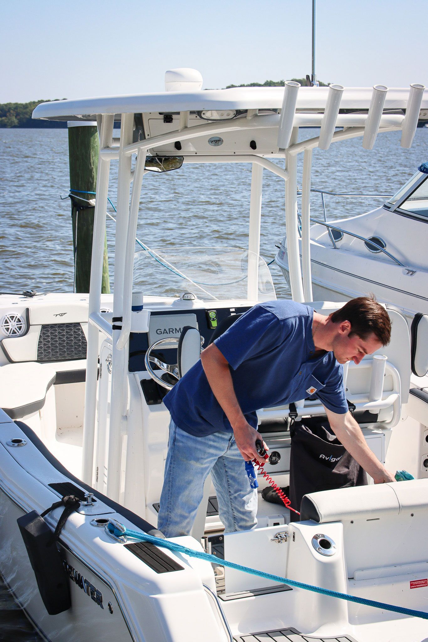 Man working on a boat deck with fishing gear on calm water under bright sun