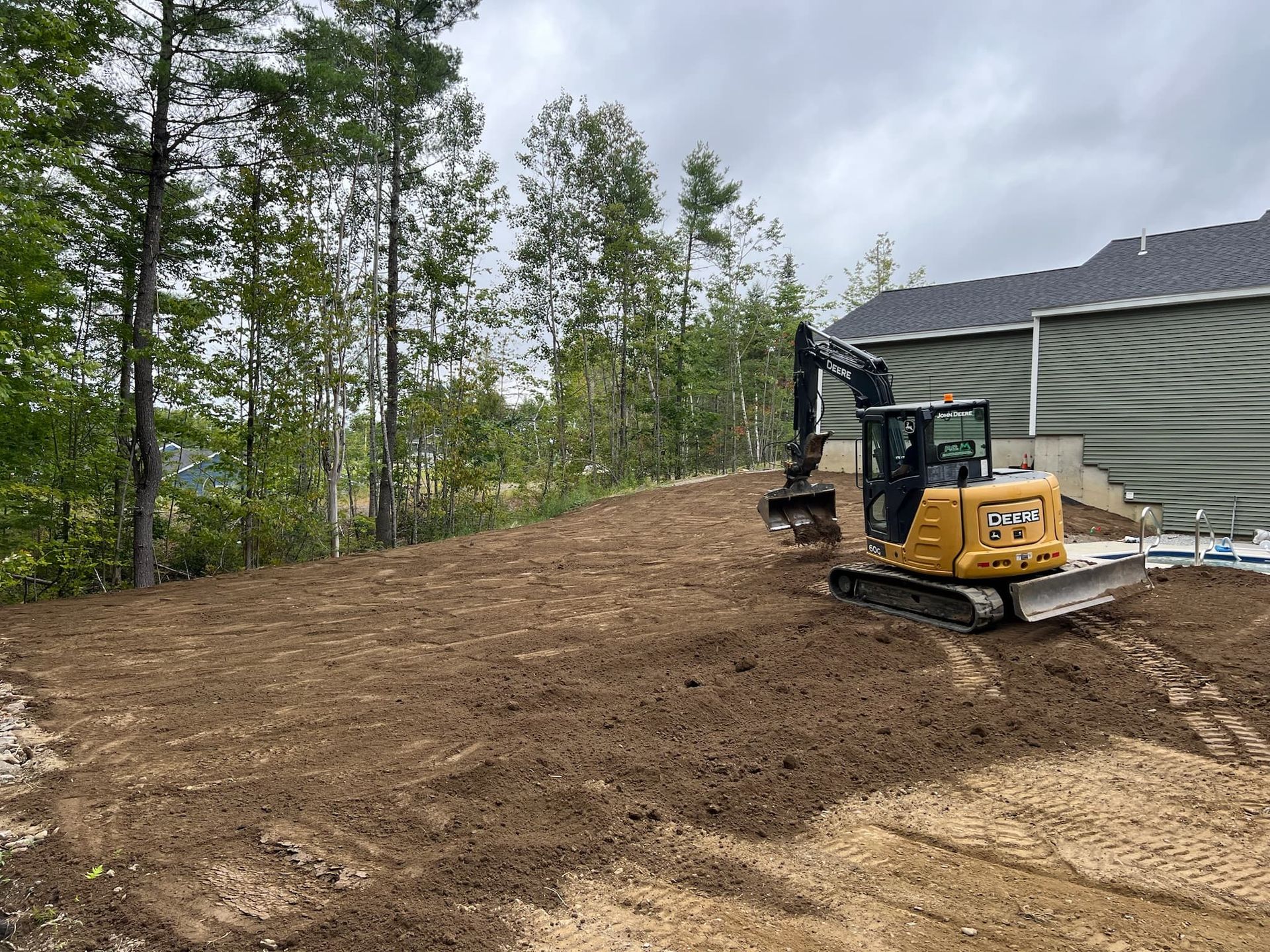 A bulldozer is working on a dirt field in front of a house.