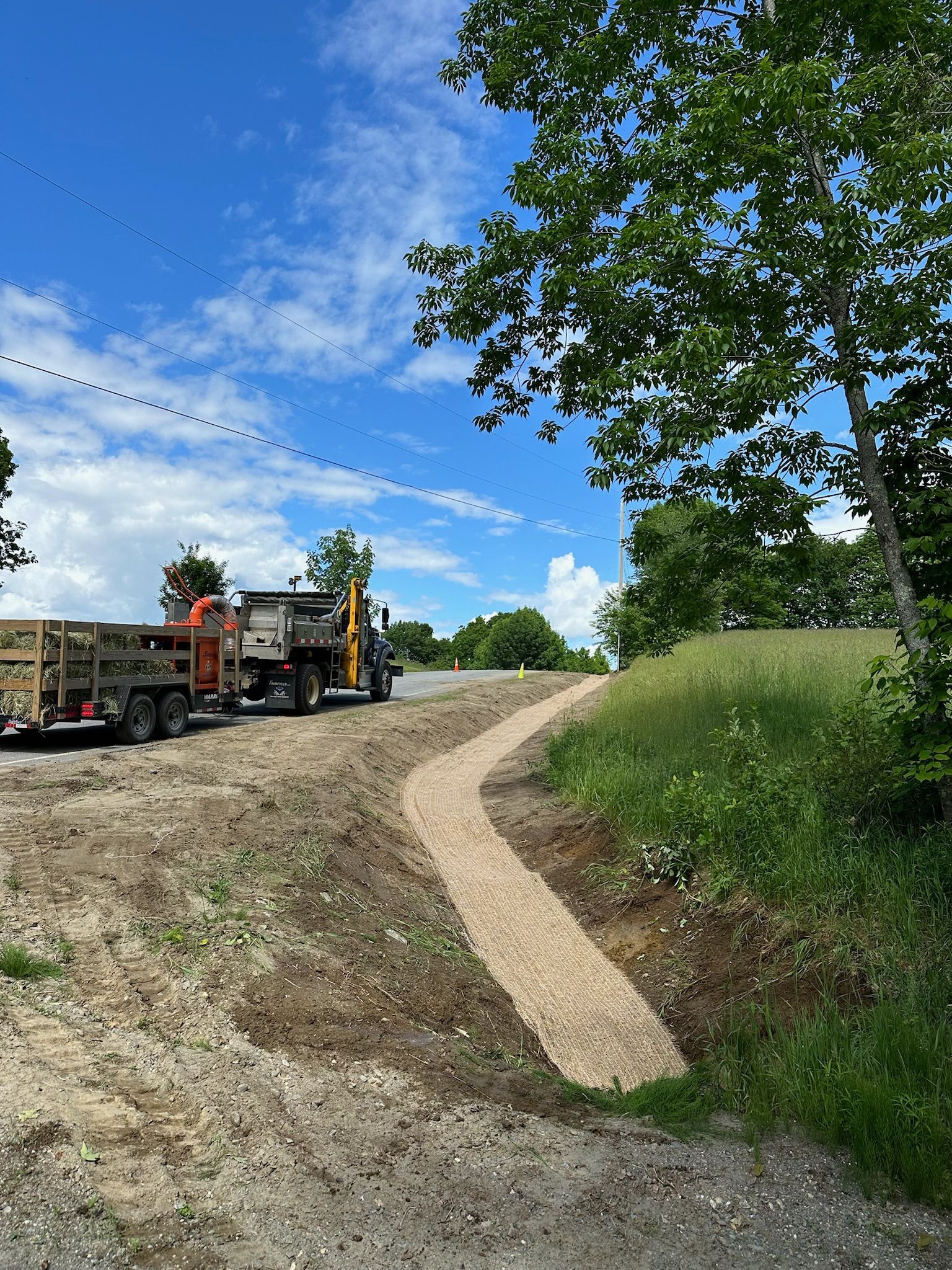 A truck is parked on the side of a dirt road next to a path.
