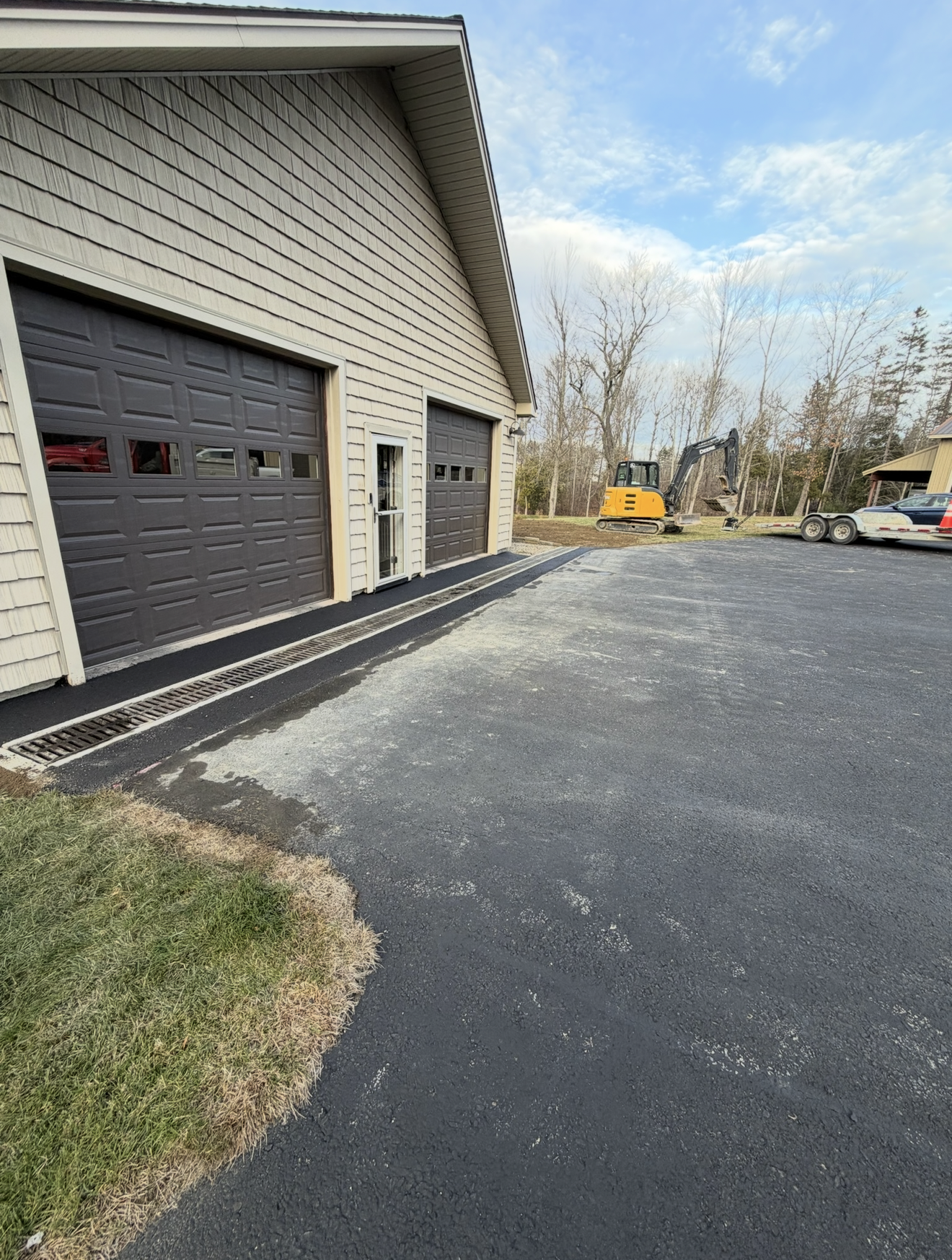A large excavator is digging a trench in front of a house.