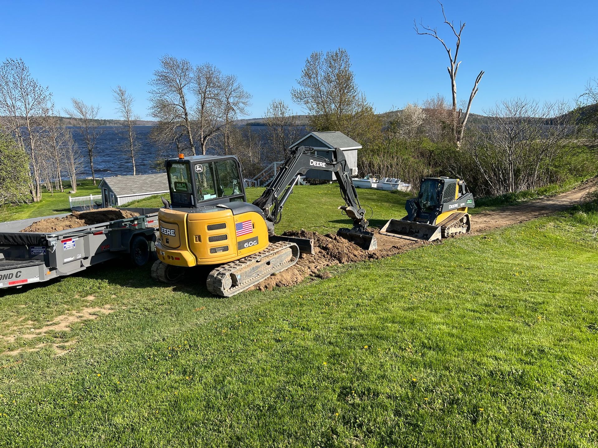 A bulldozer and an excavator are digging a hole in a grassy field.